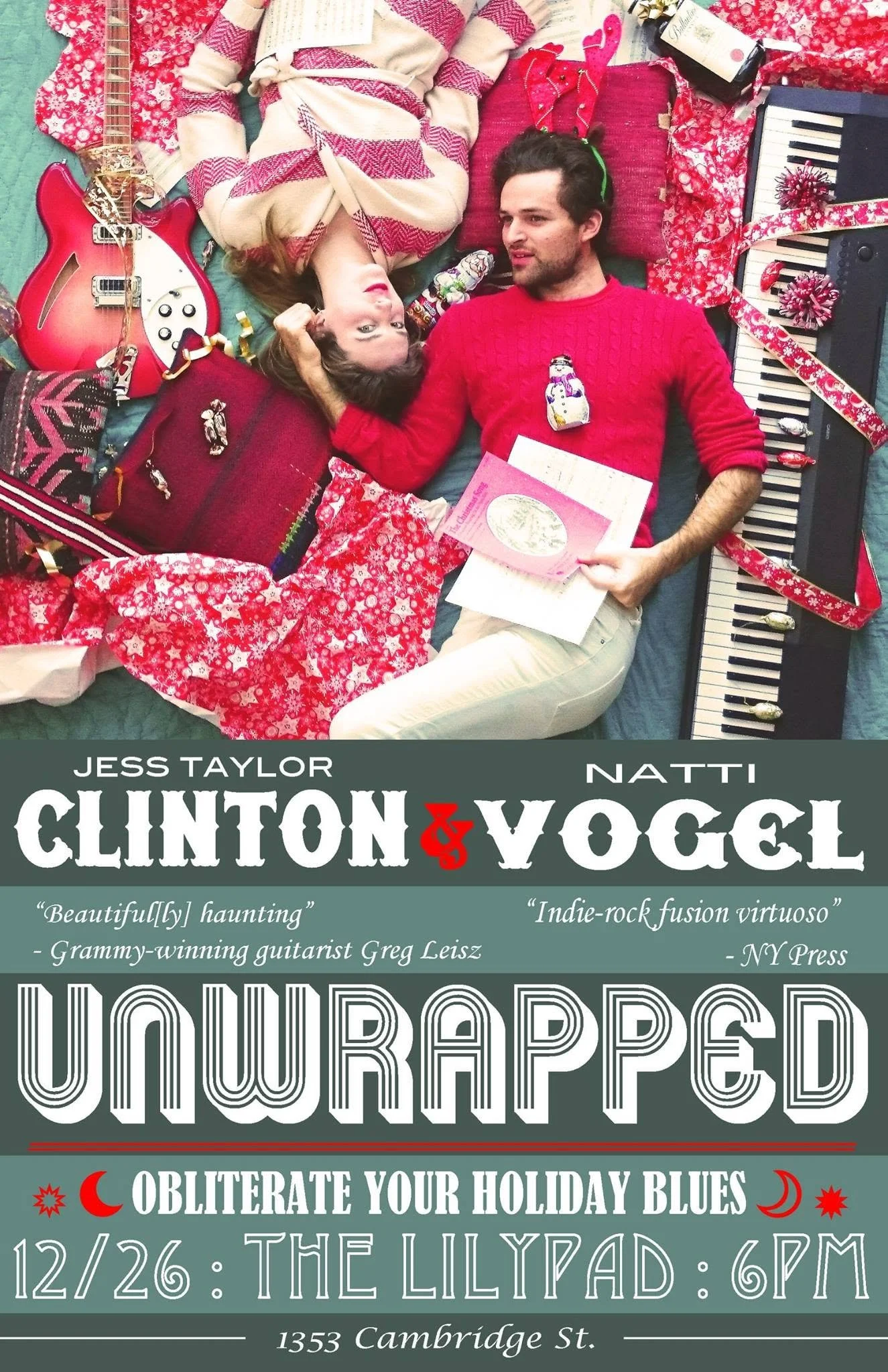 A man and woman lying on a floor surrounded by Christmas gifts, decorations, a guitar, and a keyboard. The woman is looking up, wearing a red and cream sweater, while the man is looking at her, wearing a red sweater with a snowman ornament on it.