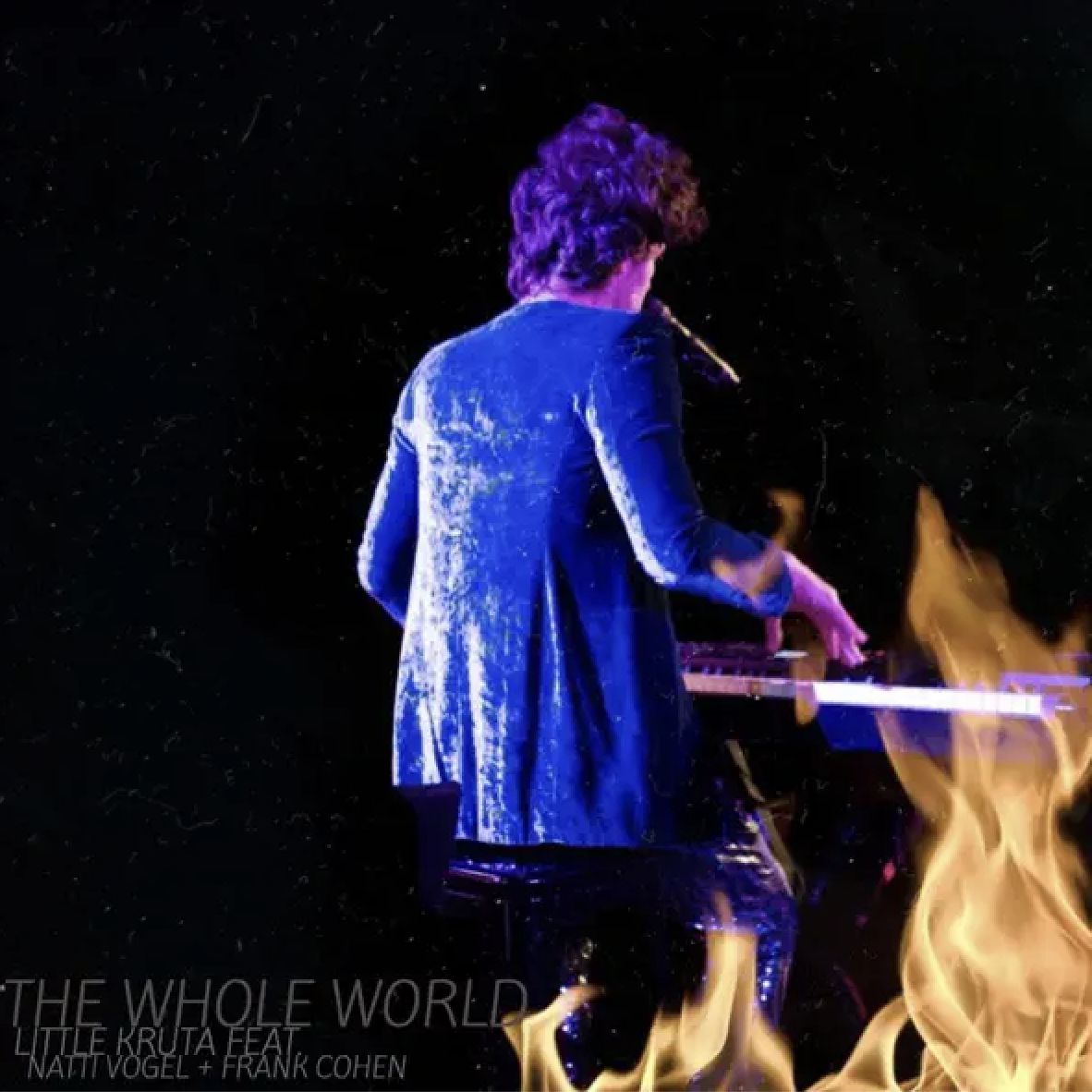 Natti Vogel playing a keyboard on stage with flames in front of them, dark background.