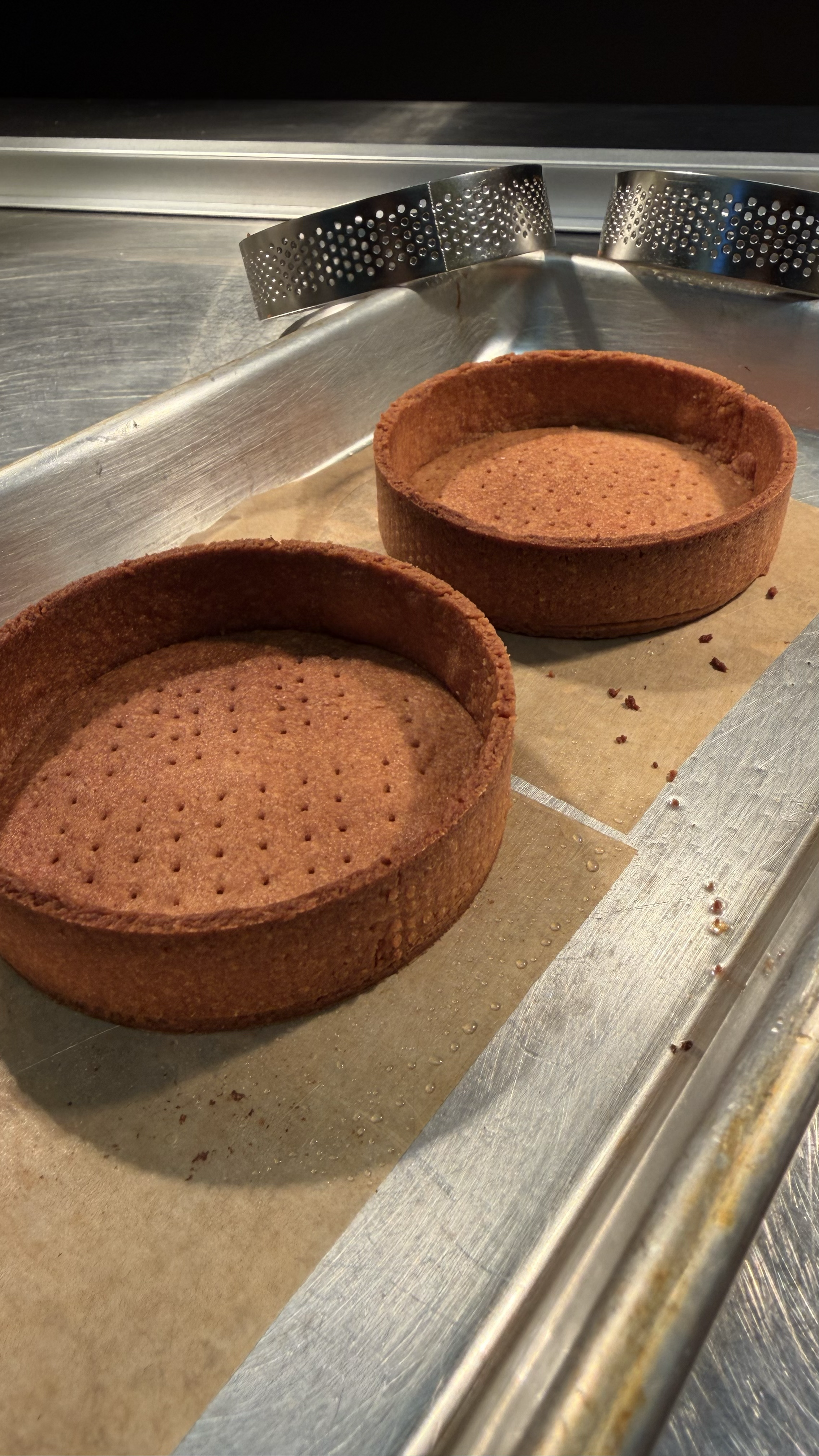 Two empty chocolate cookie tart crusts on a baking sheet