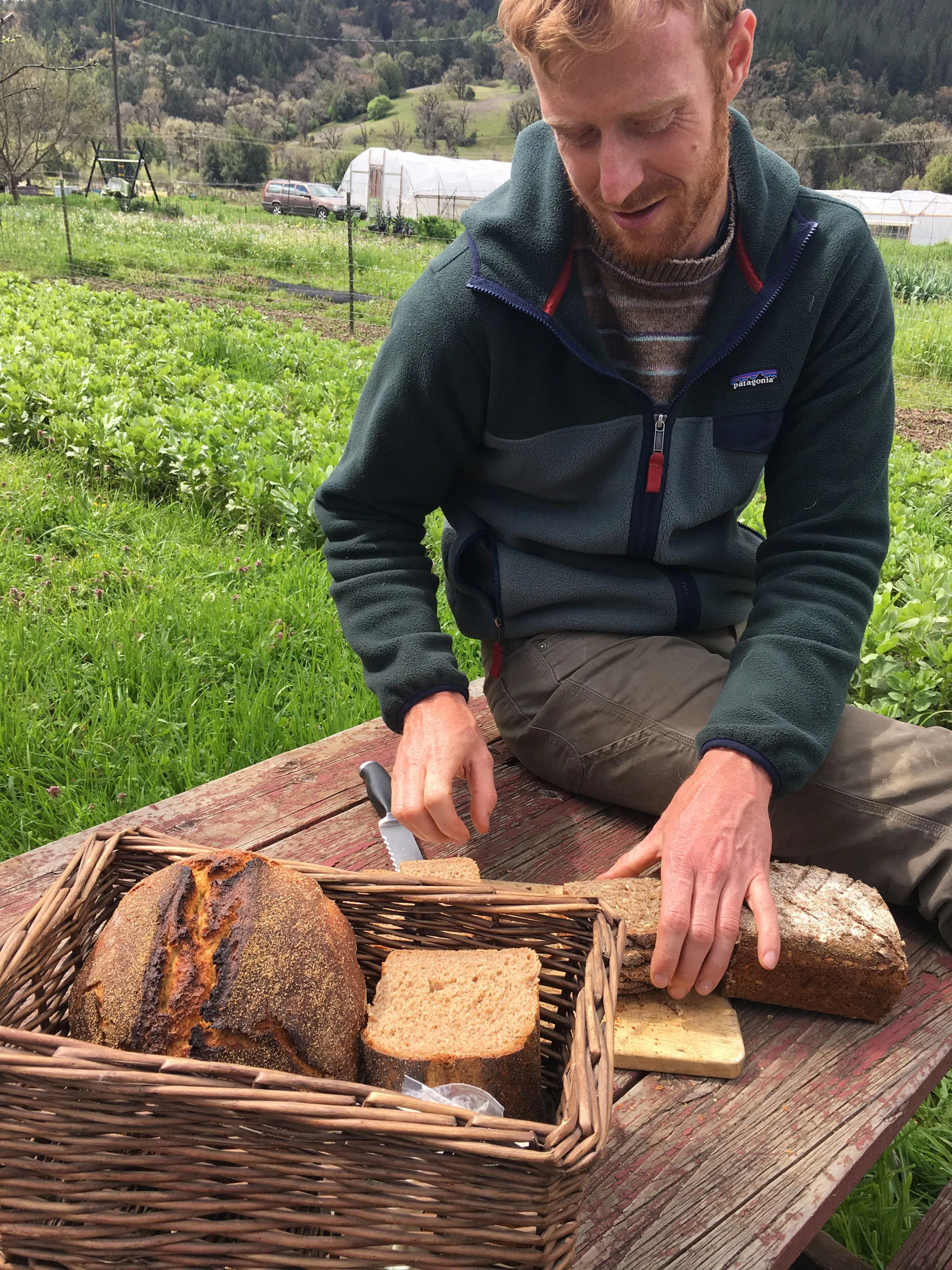 Eliot slices his bread at a picnic table
