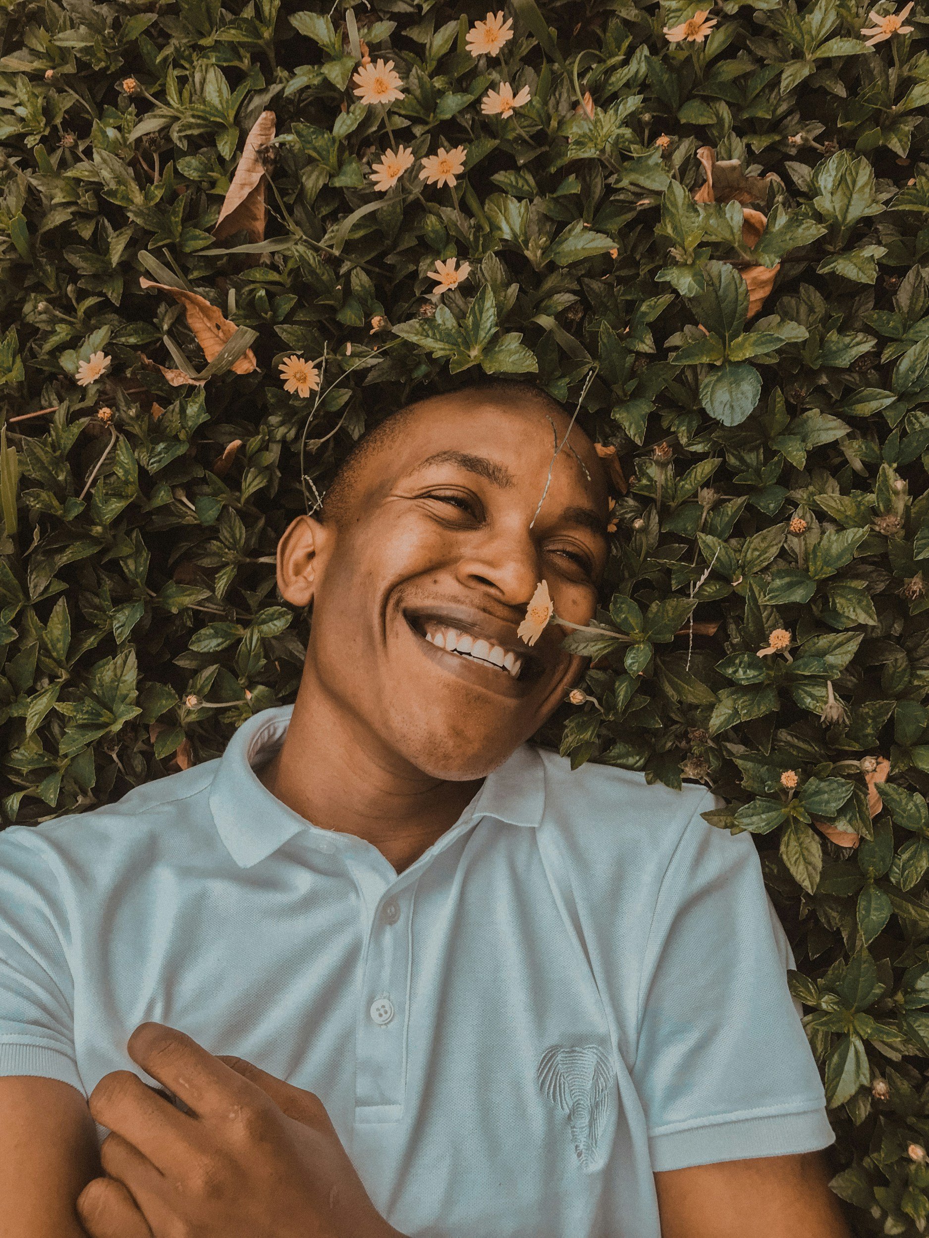 joyful man lying on bed of flowers smiling after depression therapy in Concord, NC