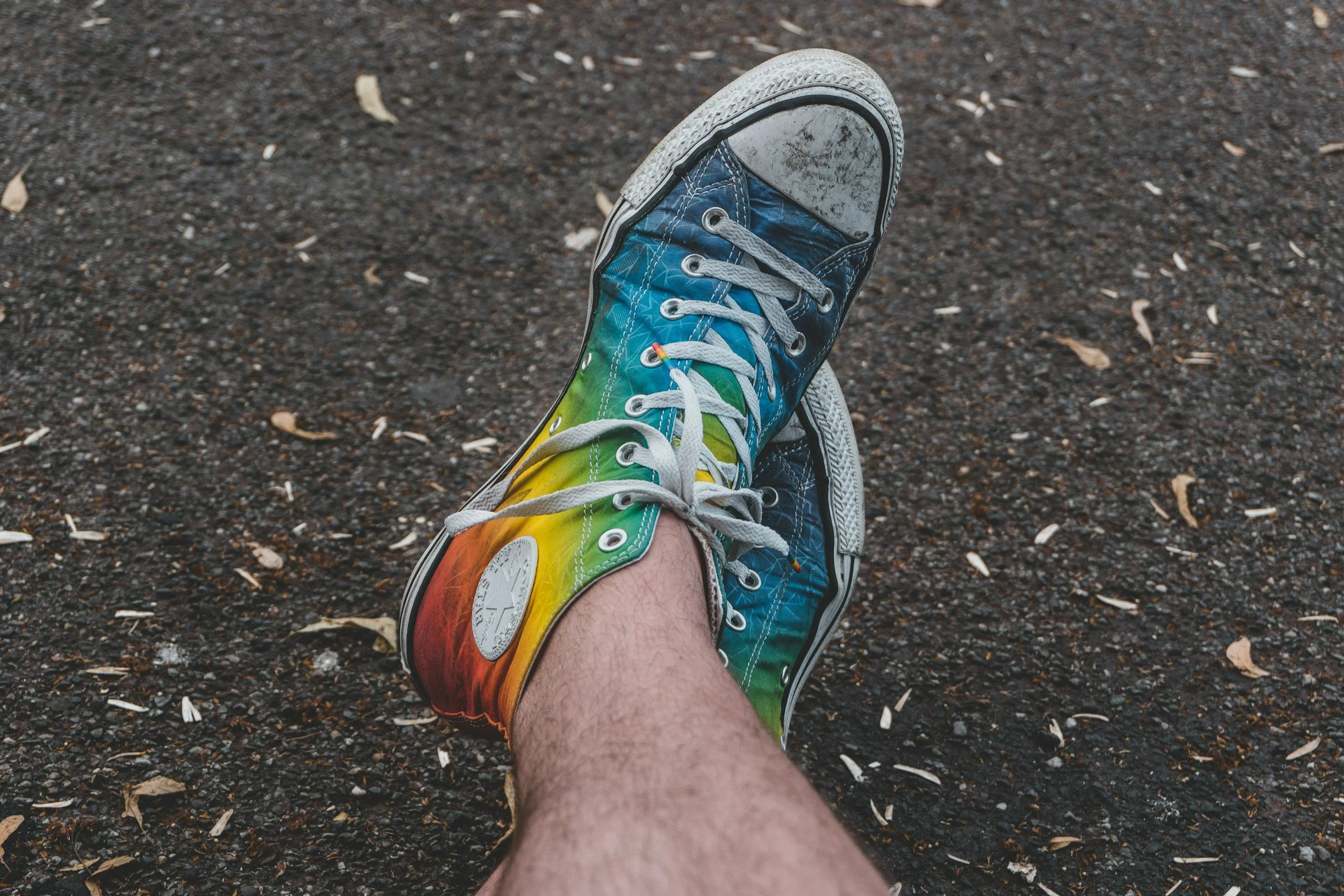 crossed legs of individual wearing rainbow colored converse shoes looking for LGBTQ therapy near Concord, NC
