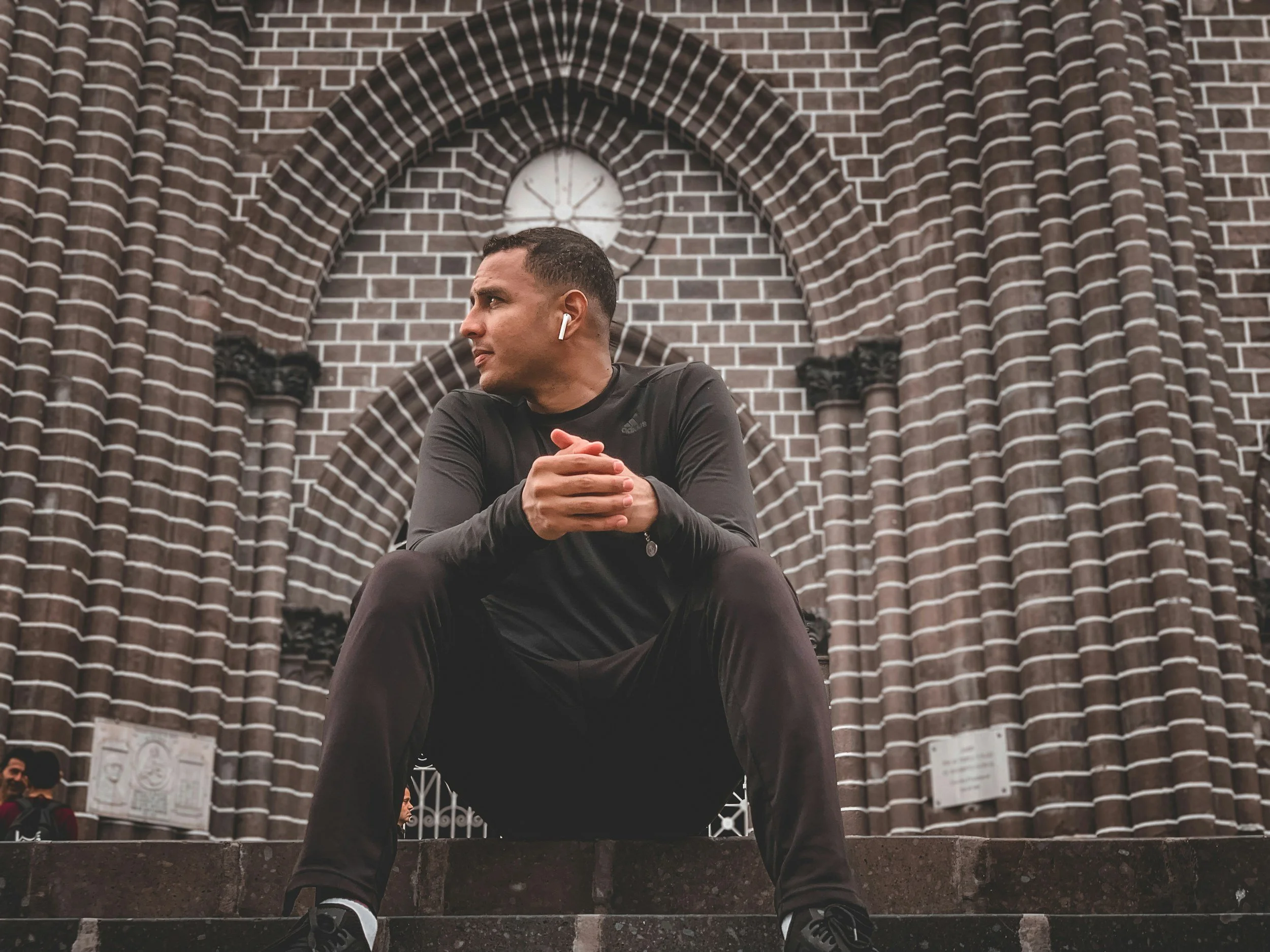 young latino man sitting on steps of brown brick building in South Carolina thinking about trauma therapy