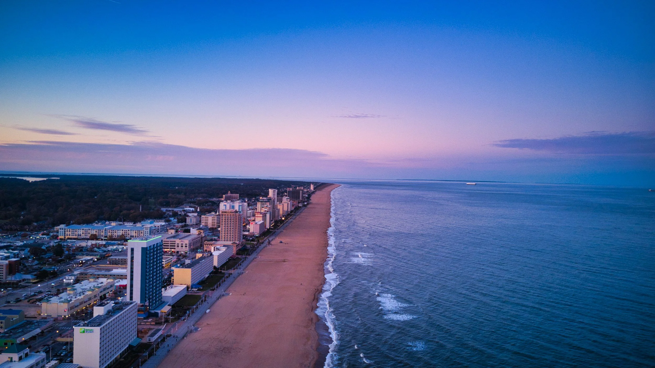 coastline of Virginia Beach with city line next to beach of sand and ocean waves