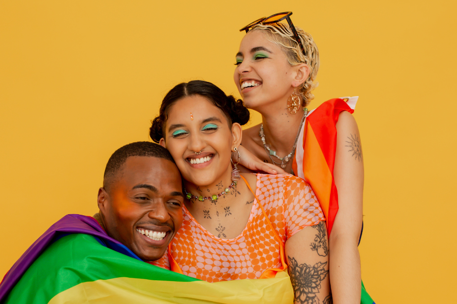 three queer people smiling and hugging