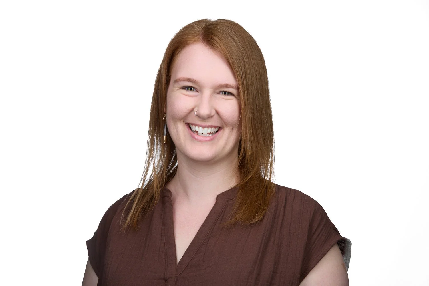 female therapist smiling with straight red hair wearing brown shirt