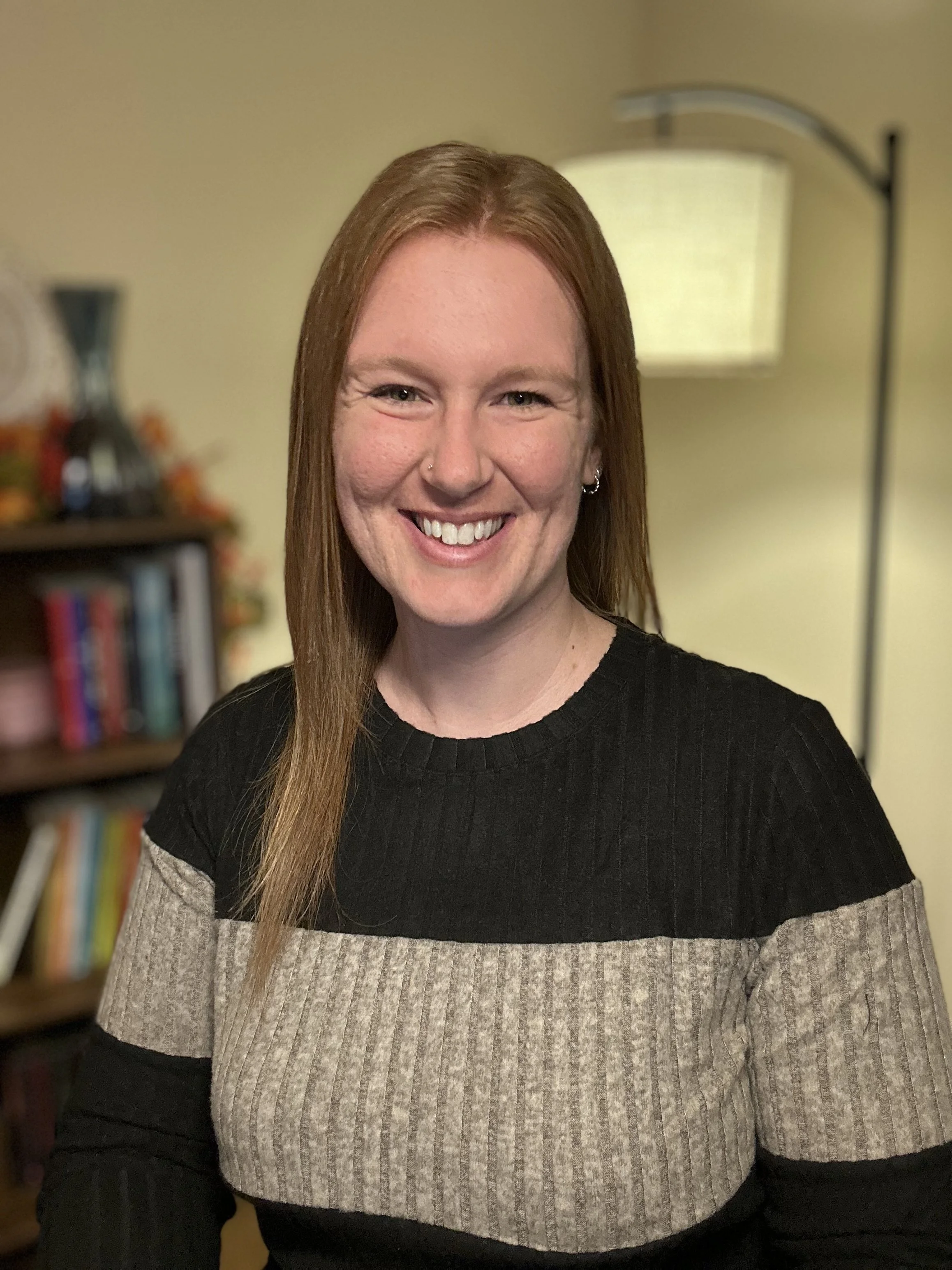 Michelle Reinhard, LCSW holistic trauma therapist female with red hair in black and brown striped shirt