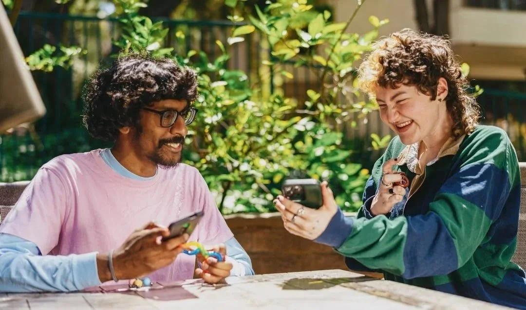 two friends sitting at outdoor table smiling after session with trauma therapist