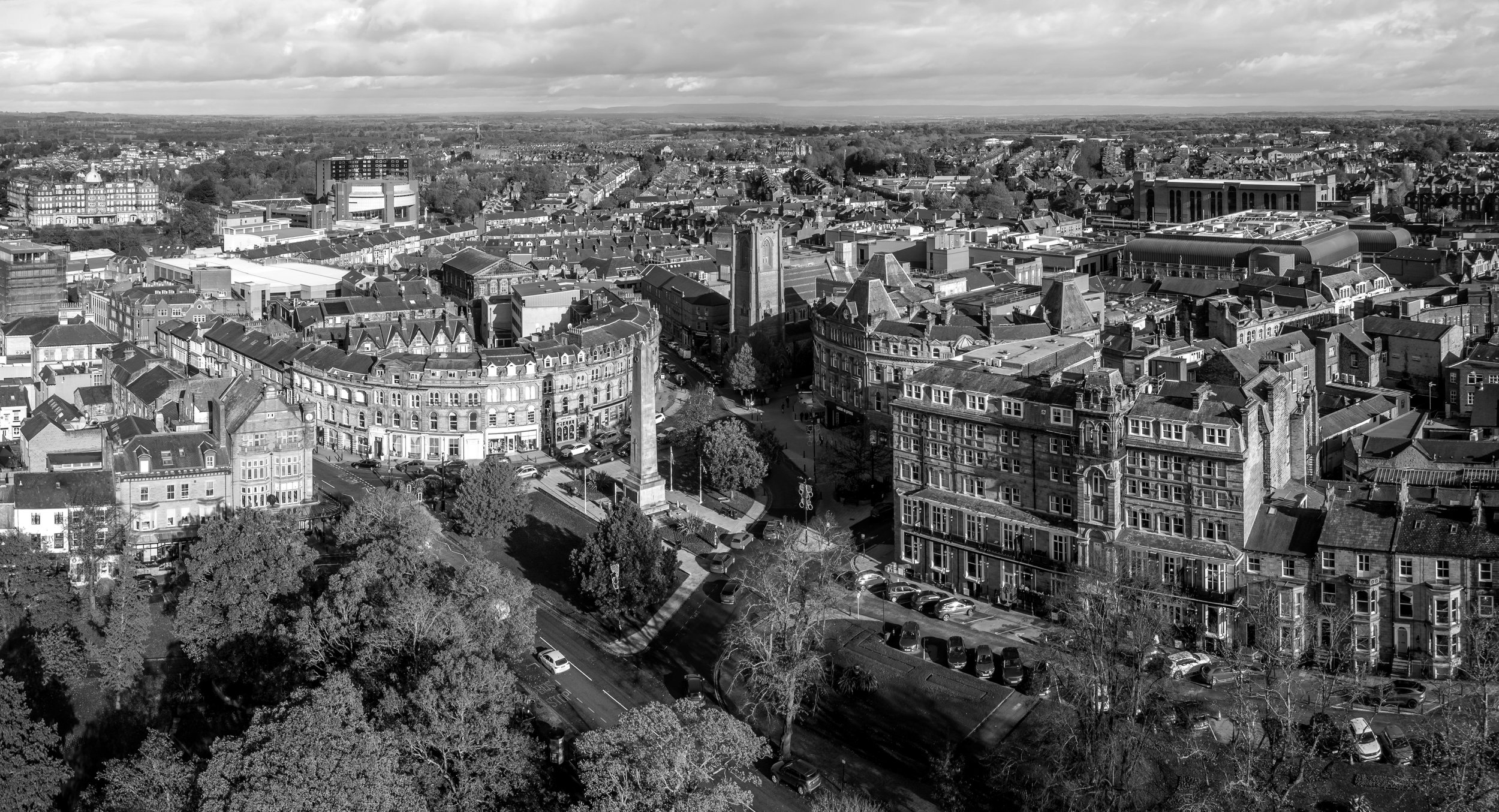 Aerial black and white photograph of Harrogate Town Centre with historic buildings, the cenotaph, shops and tree-lined streets.