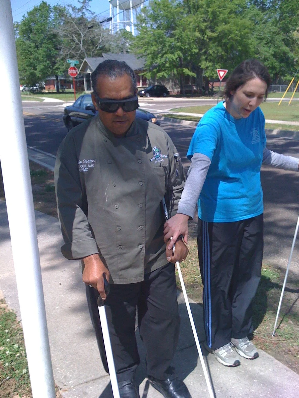 TLC student learning to walk with cane with the assistance from an instructor