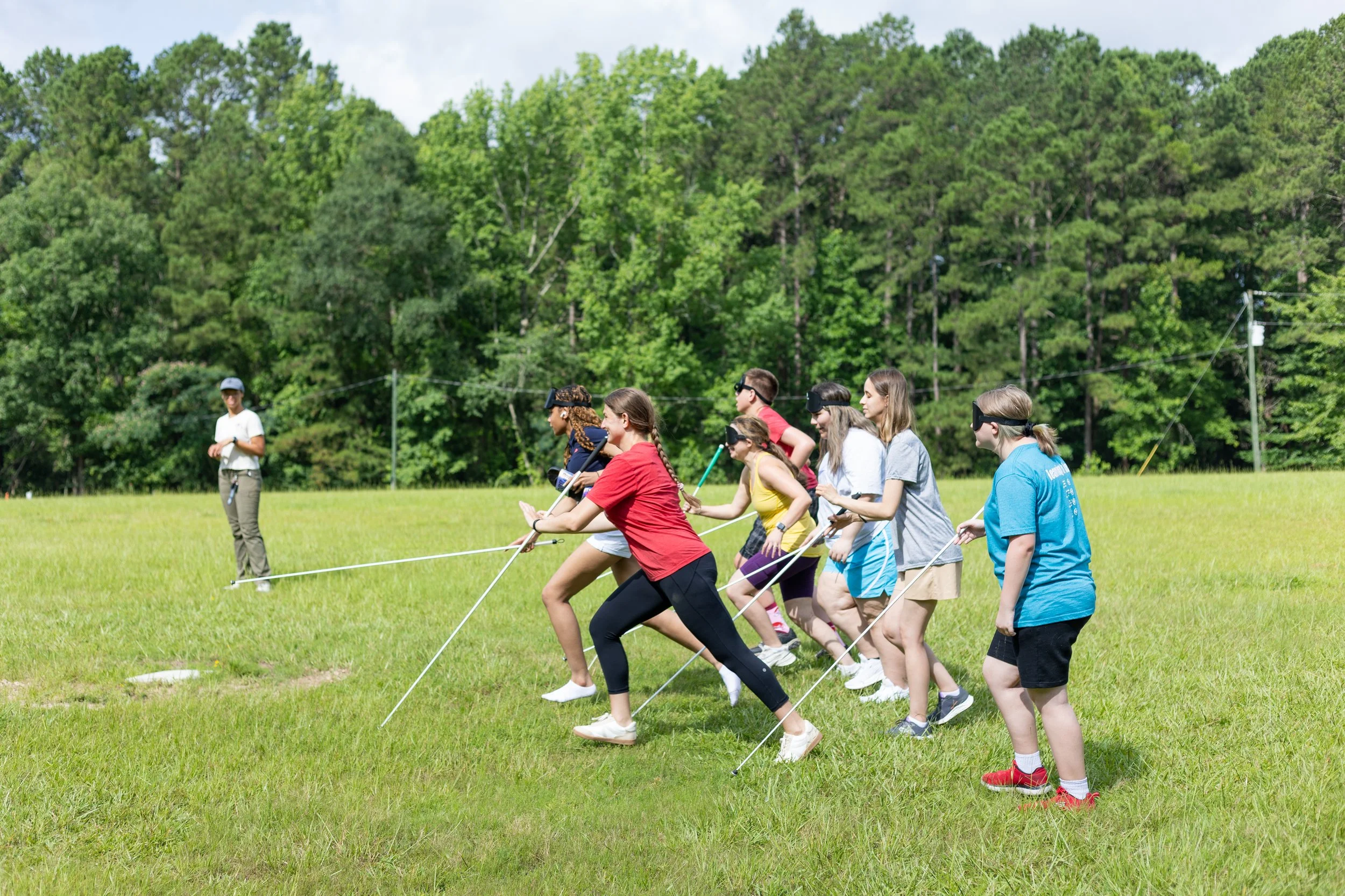 Summer teens running across a field with their canes