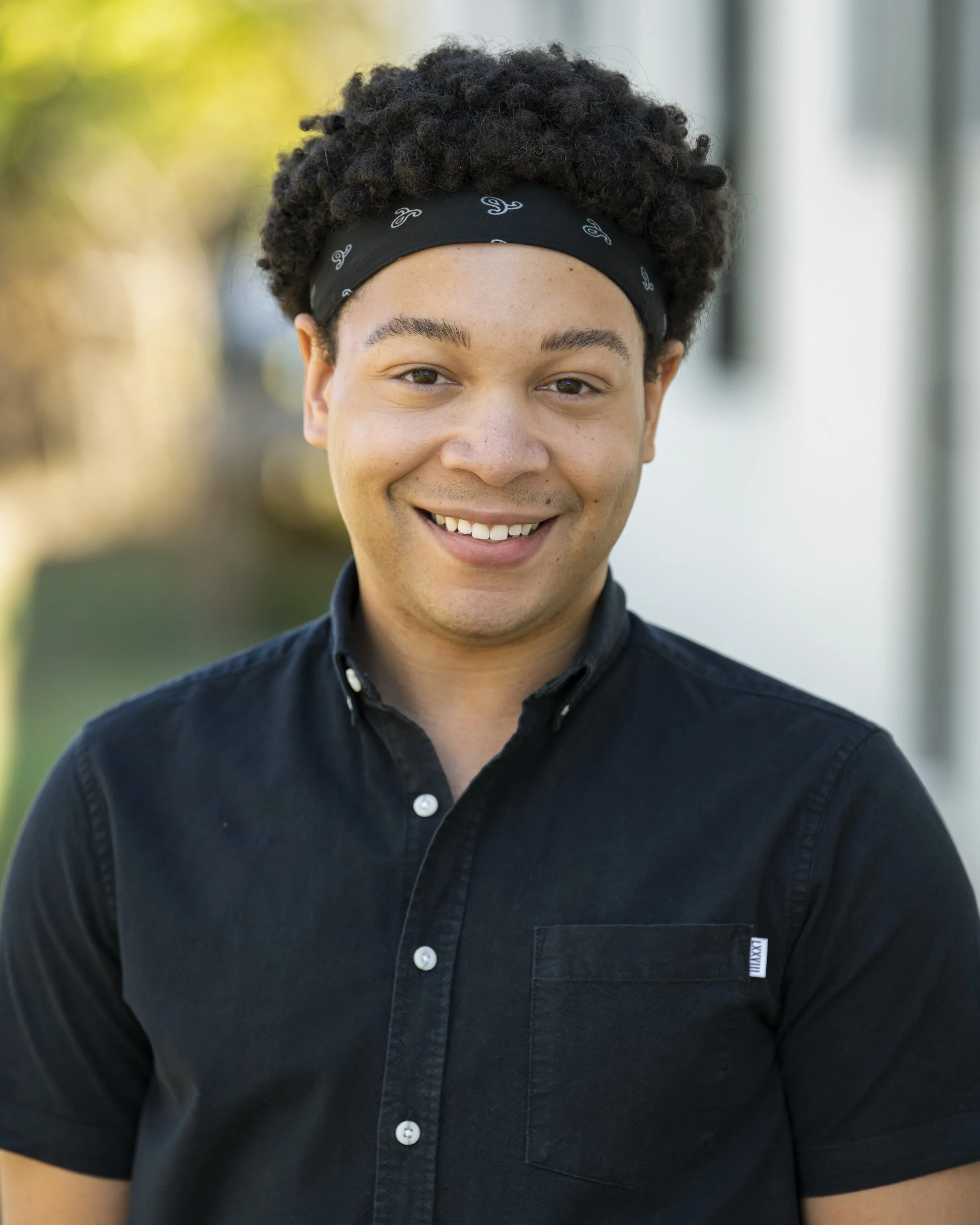 Headshot of Corey Dodd, a young man smiling outdoors wearing a dark shirt