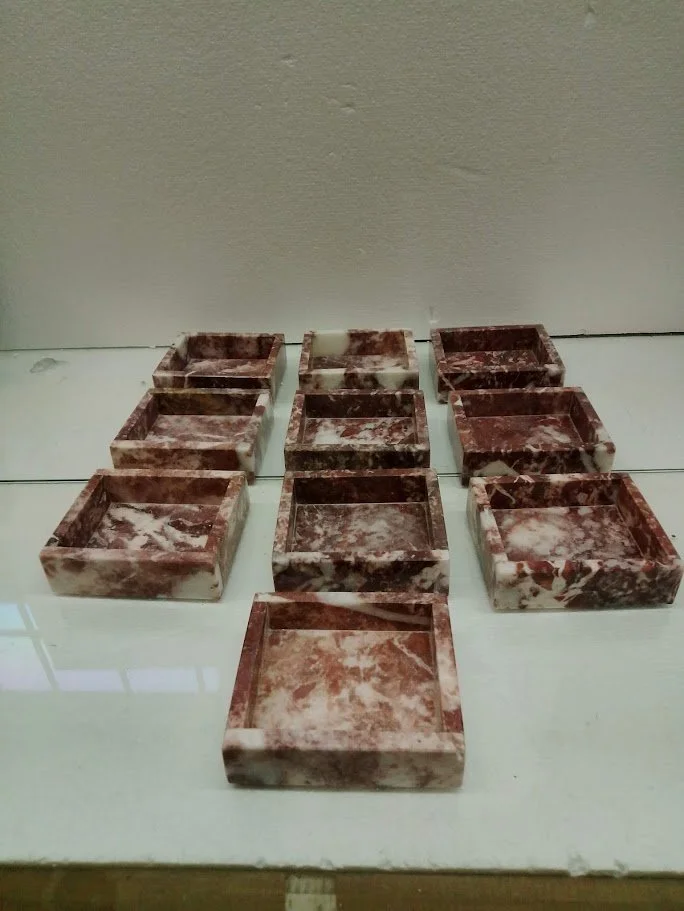 Nine small rectangular marble trays arranged in three rows of three on a glass surface.