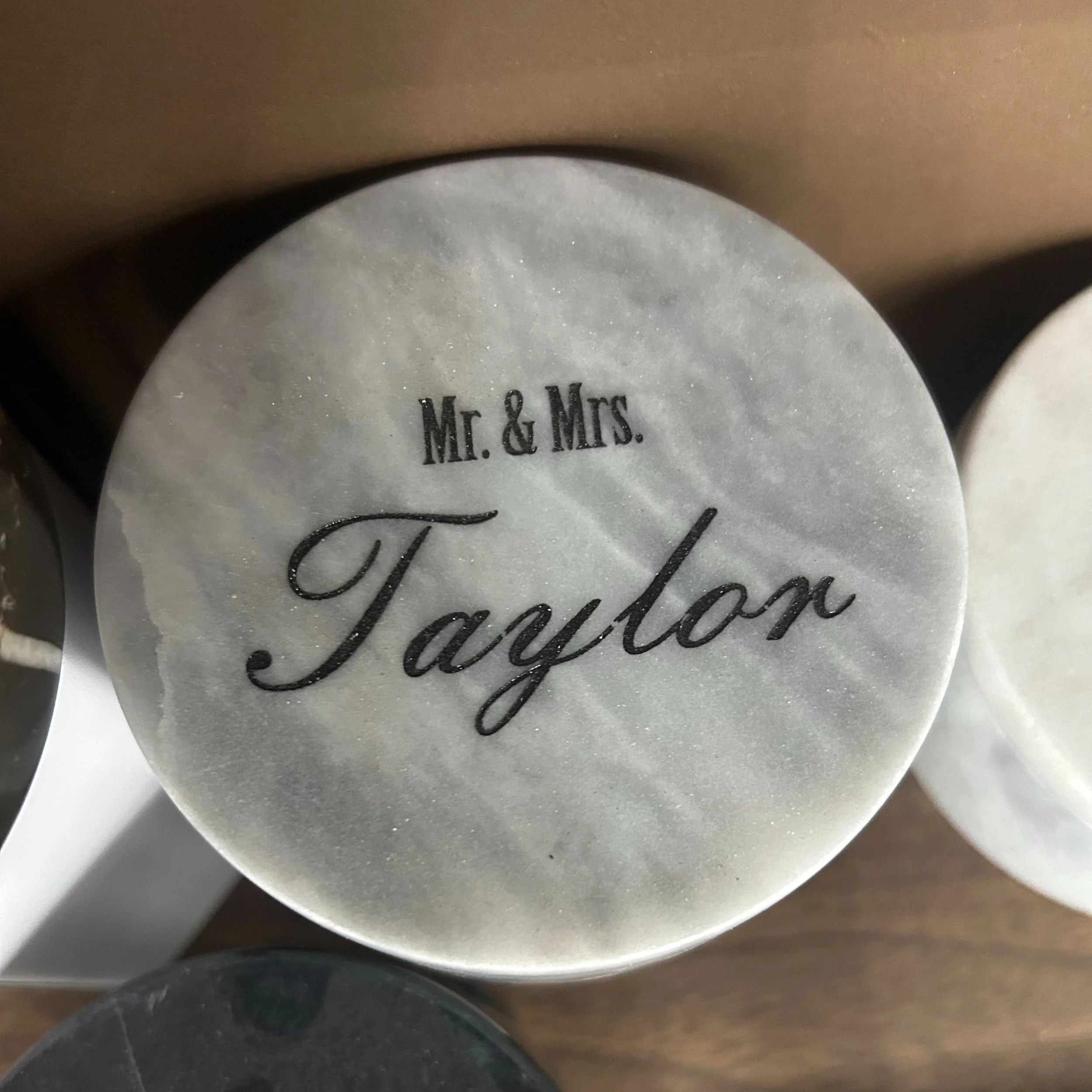 A round candle with the text 'Mr. & Mrs. Taylor' on it, placed on a wooden surface.