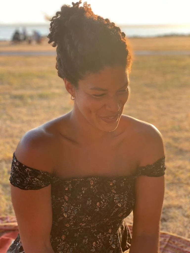 Aja, life transition coach for women, smiling outdoors in natural light.
