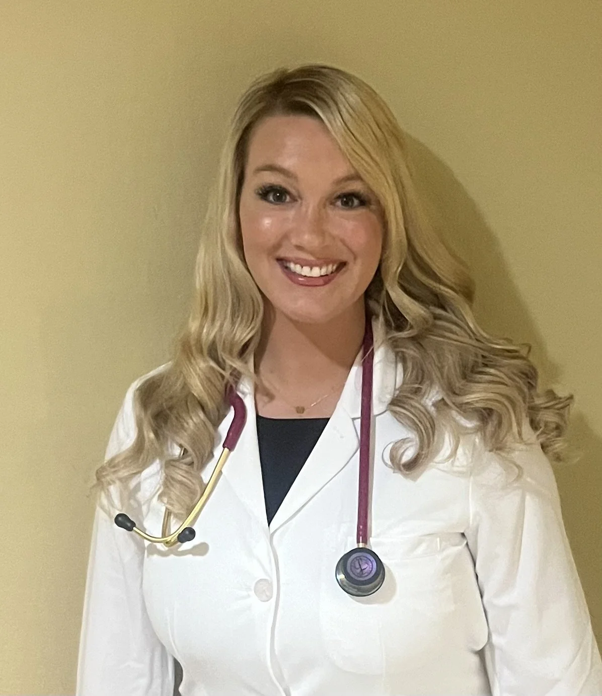 A smiling female healthcare professional wearing a white lab coat and stethoscope around her neck. Midwife, midwifery
