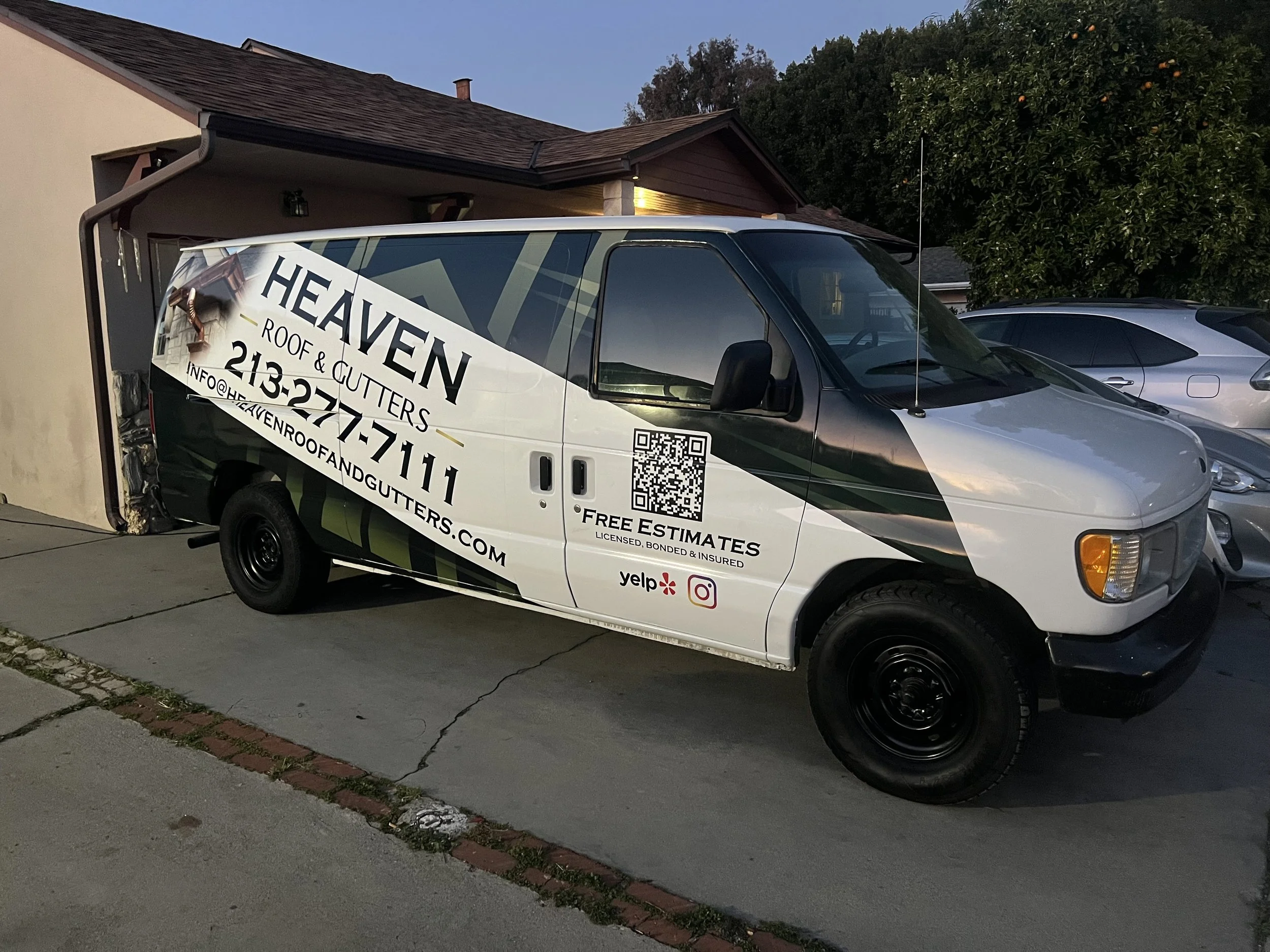 White van parked outside with advertising for Heaven Roof & Gutters, featuring company name and contact information, including a QR code, and logos for Yelp and Instagram | Grizzly Signs | Los Angeles, CA | Custom Wraps