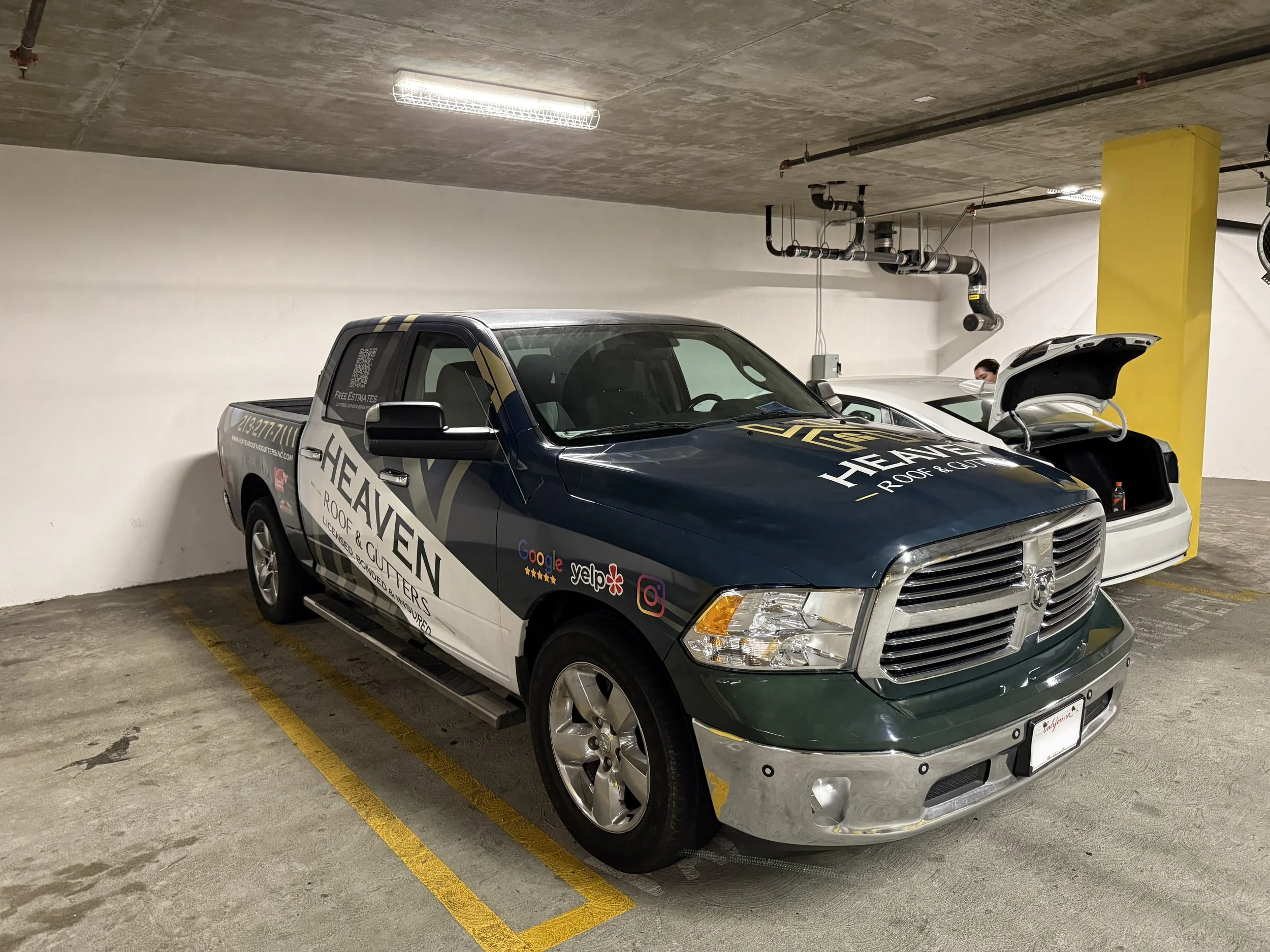 A dark green and silver pickup truck with advertising for Heaven Roof & Gutters is parked in an underground parking garage. | Grizzly Signs | Los Angeles, CA | Custom Wraps