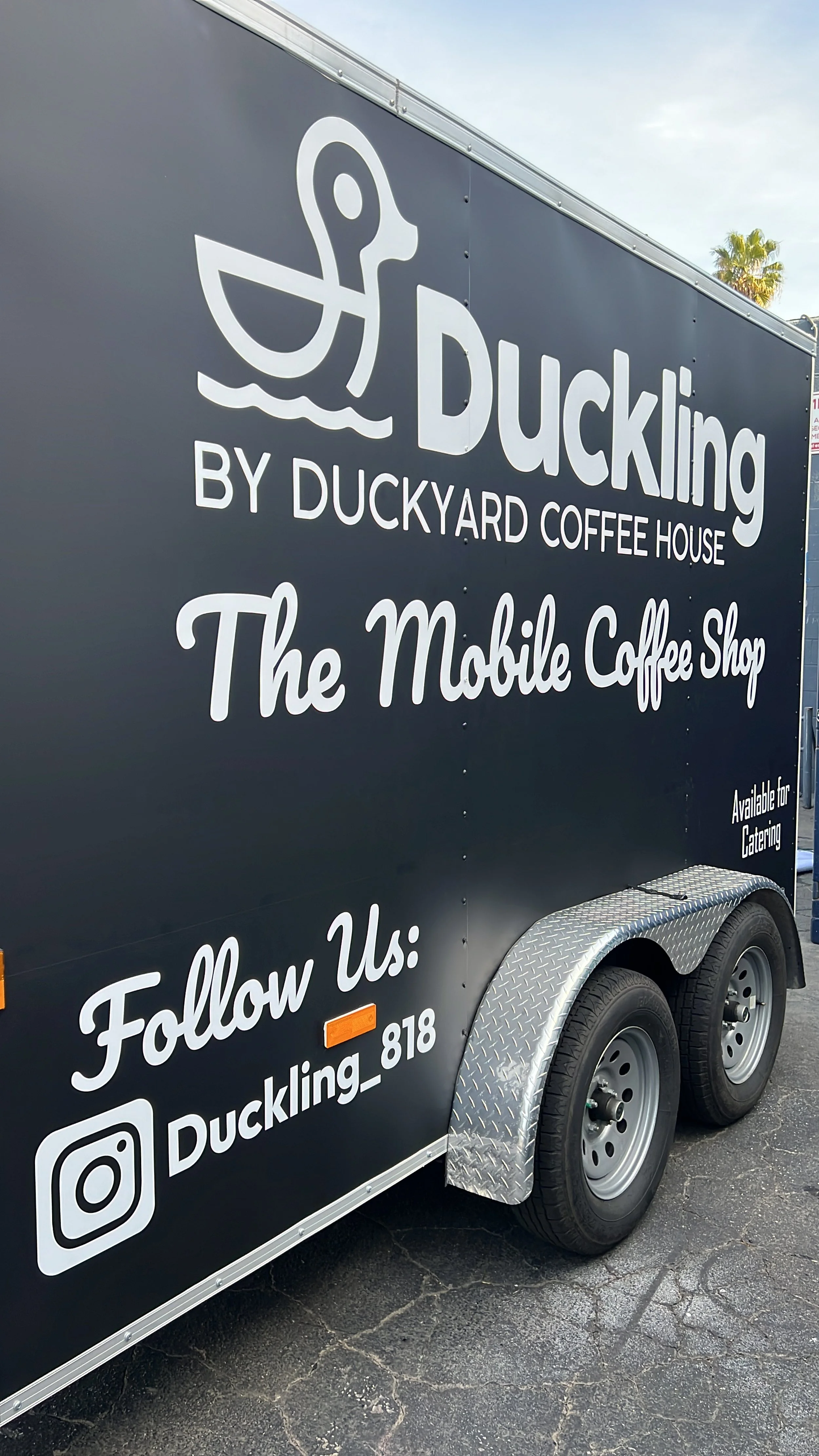 Black mobile coffee shop trailer with white lettering and a duck logo, advertising Duckling by Duckyard Coffee House and encouraging followers on Instagram | Grizzly Signs | Los Angeles, CA | Custom Wraps