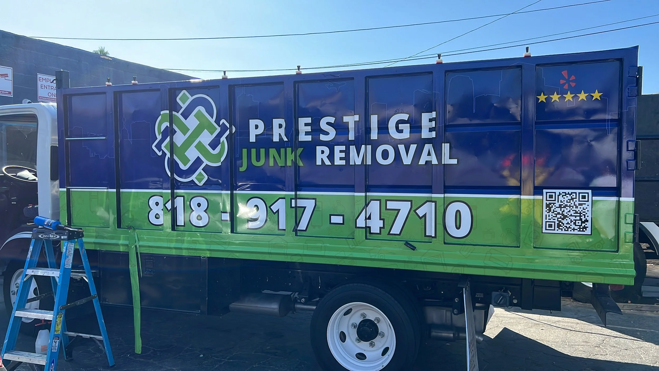 A mobile billboard for Prestige Junk Removal featuring a blue and green design with a logo, phone number, QR code, and decorative stars | Grizzly Signs | Los Angeles, CA | Custom Wraps