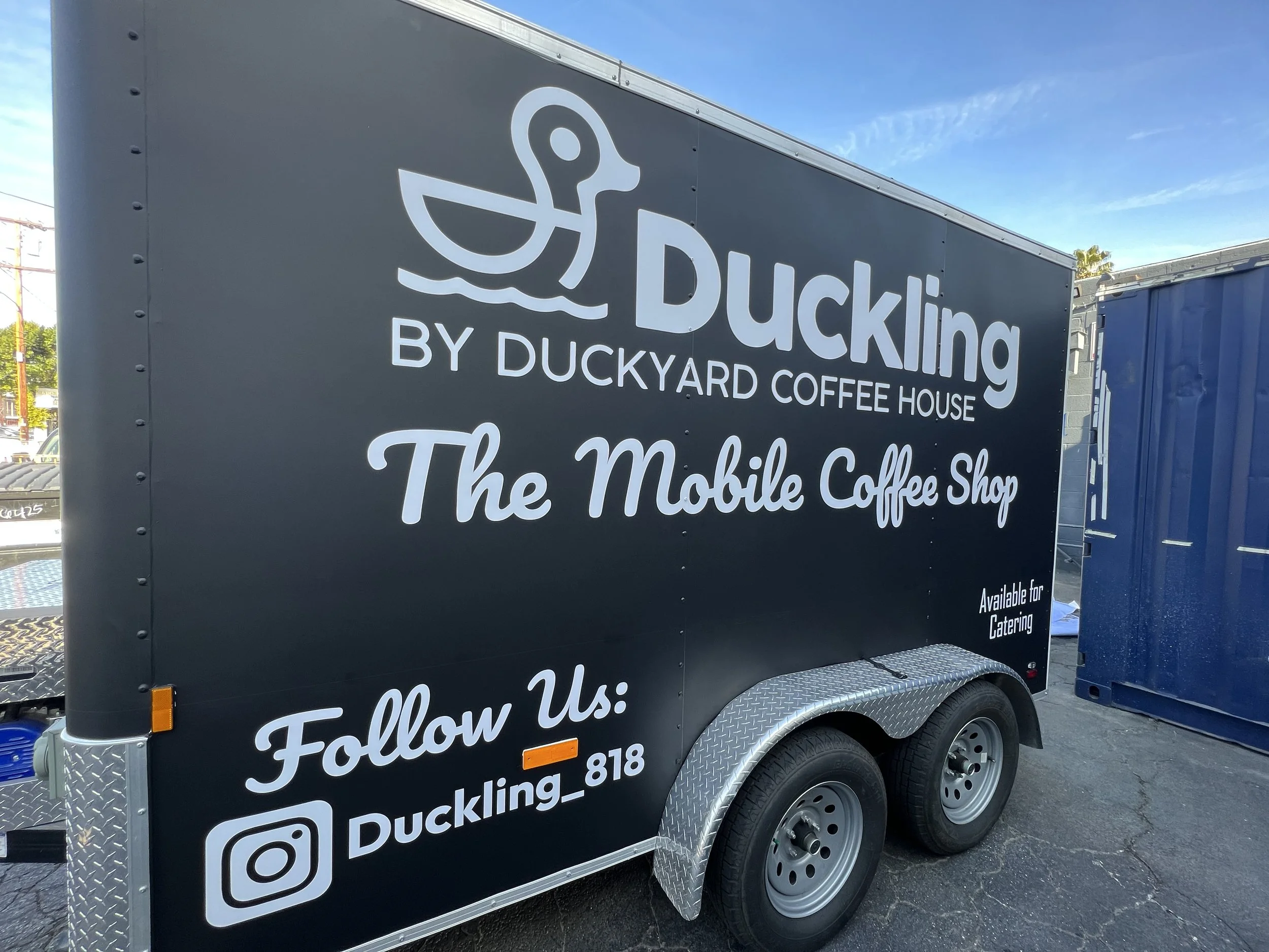 A mobile coffee shop trailer with the branding 'Duckling by Duckyard Coffee House,' featuring a duck logo and social media handle | Grizzly Signs | Los Angeles, CA | Custom Wraps