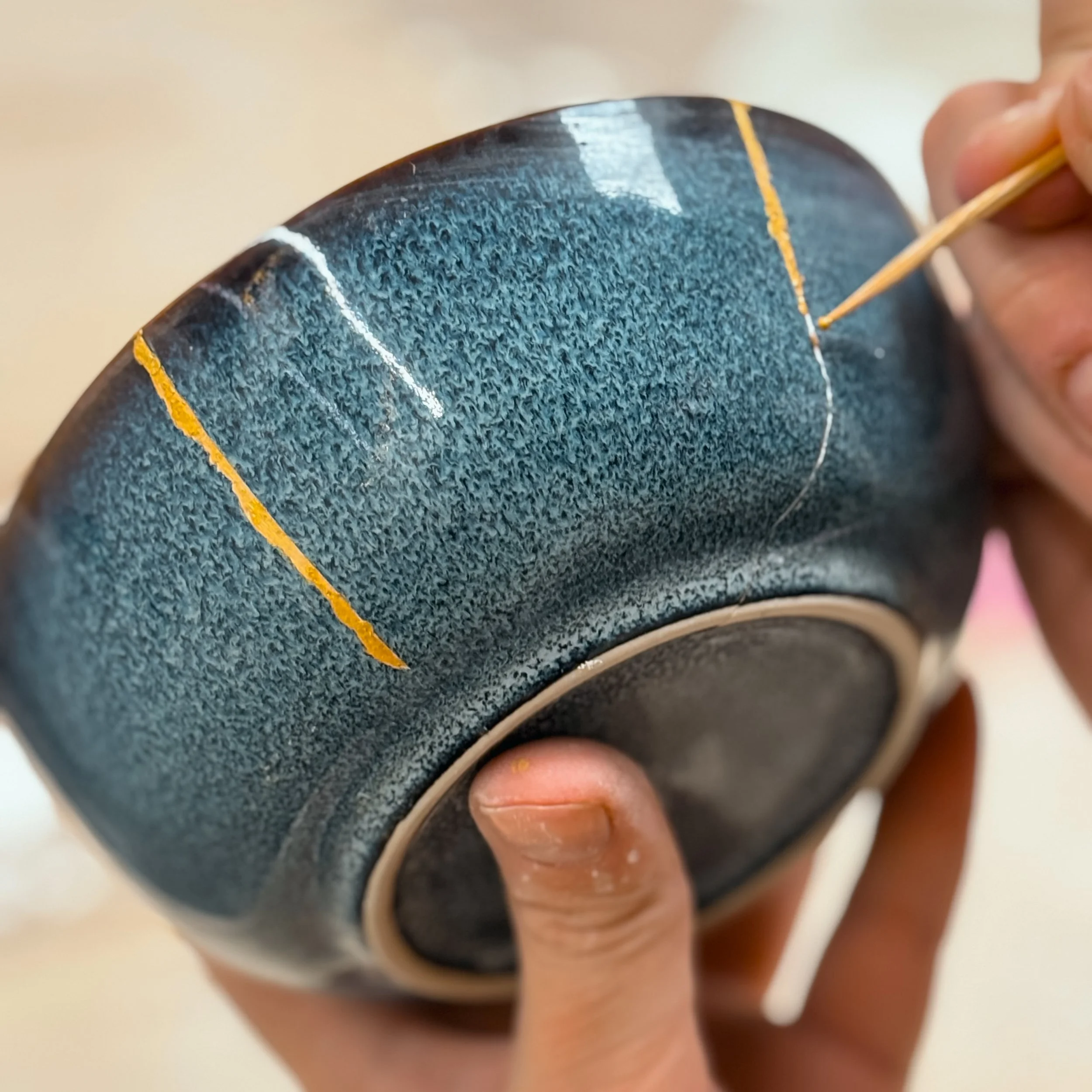 Una persona sta riparando una cassa audio rotta con del nastro adesivo e l'uso di uno stuzzicadenti.