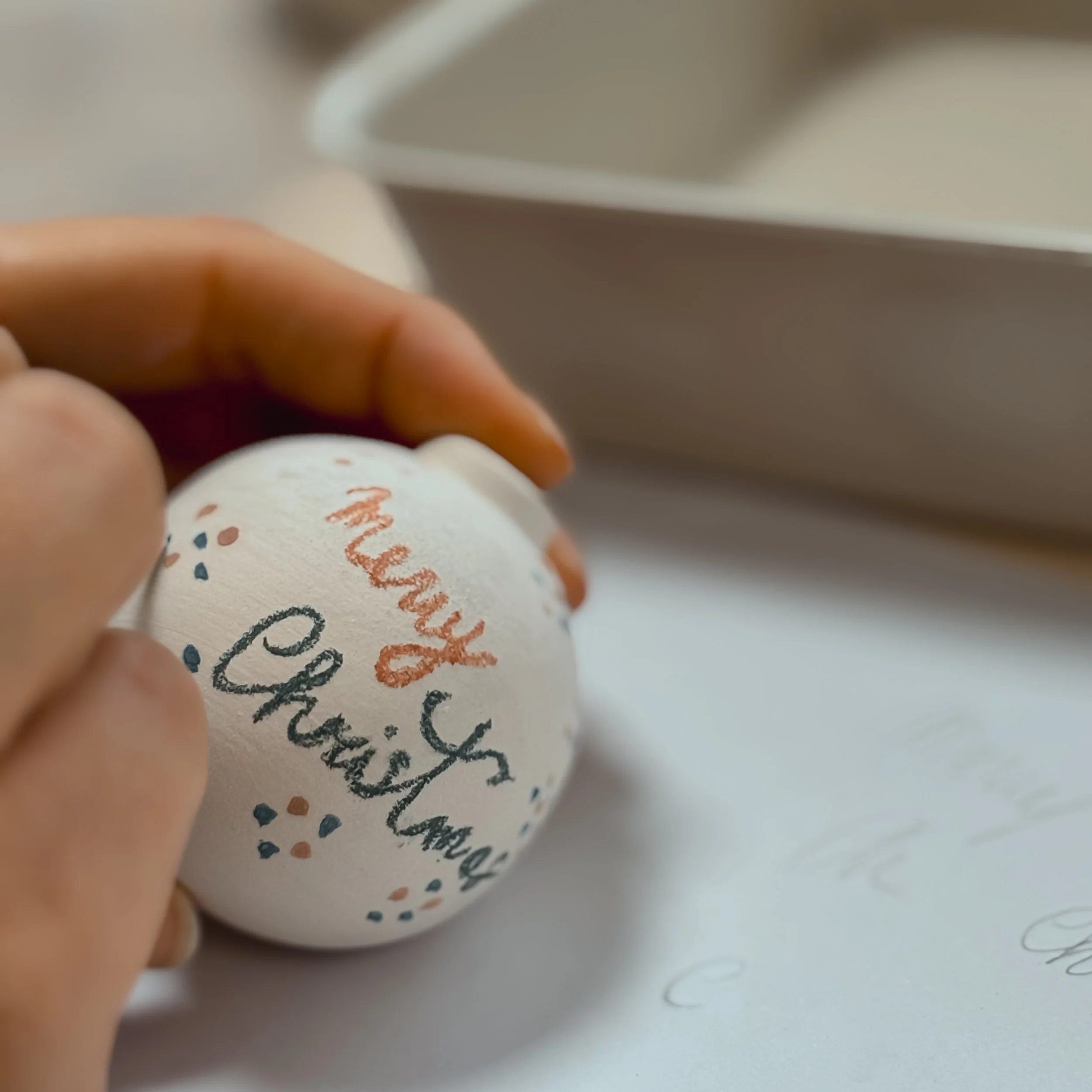 Una mano che dipinge un uovo di Pasqua con i nomi di famiglia.