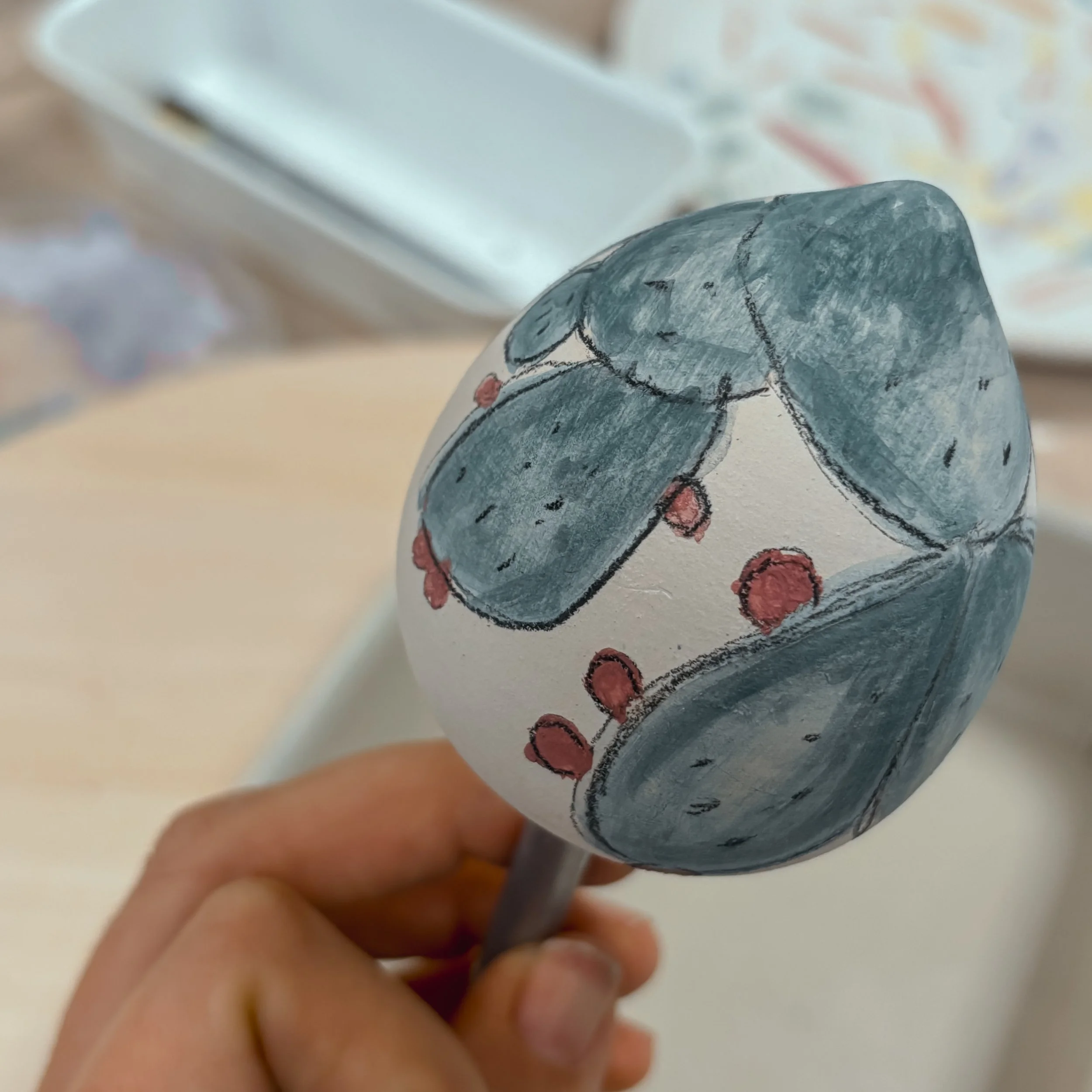 Uovo di Pasqua decorato con disegni di foglie di colore grigio e piccoli frutti rossi.