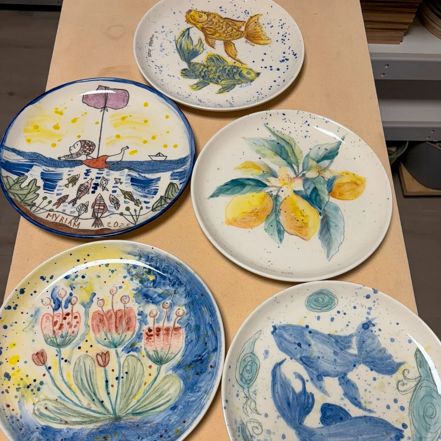 Piatti decorativi con disegni di pesci, fiori e elementi naturali, dipinti a mano con colori vivaci.