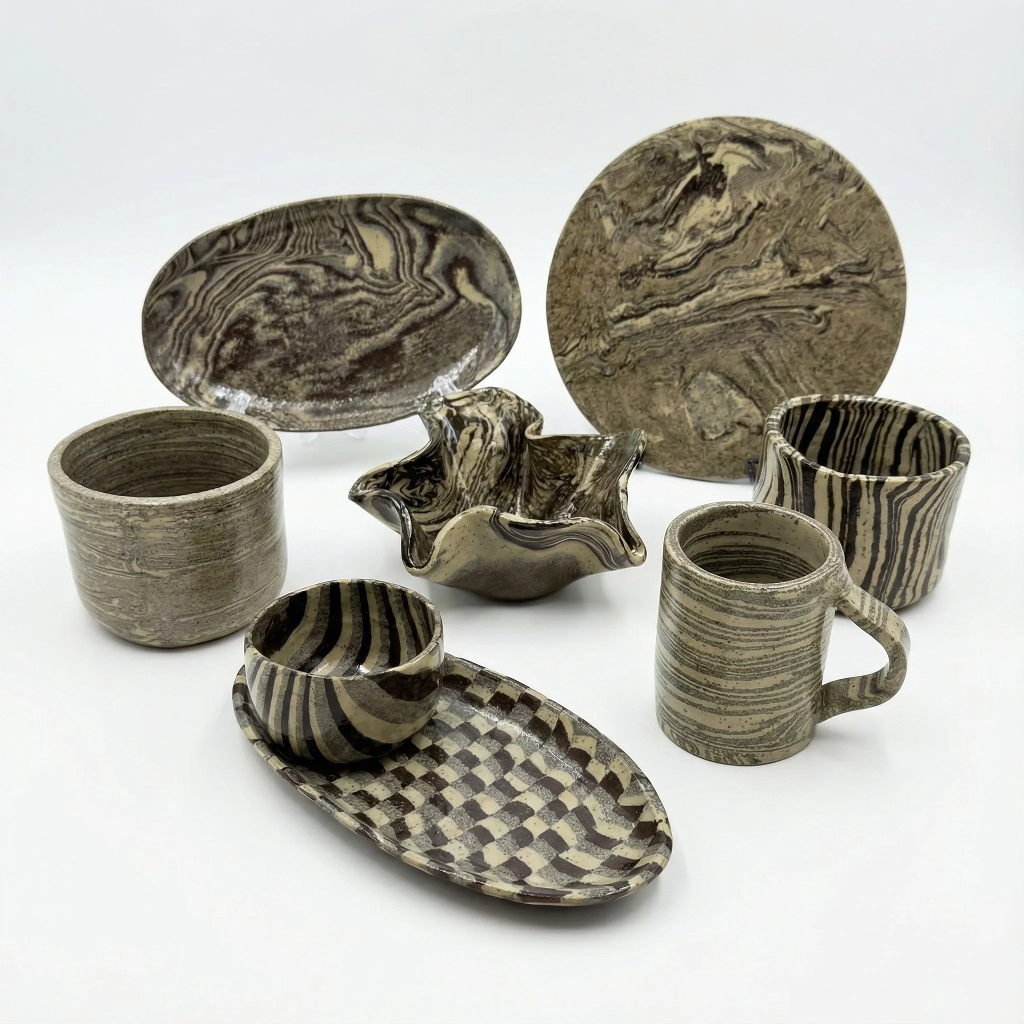 Set di ceramiche artistiche con motivi marmorizzati in toni neutri, costituito da piatti, ciotole e tazze