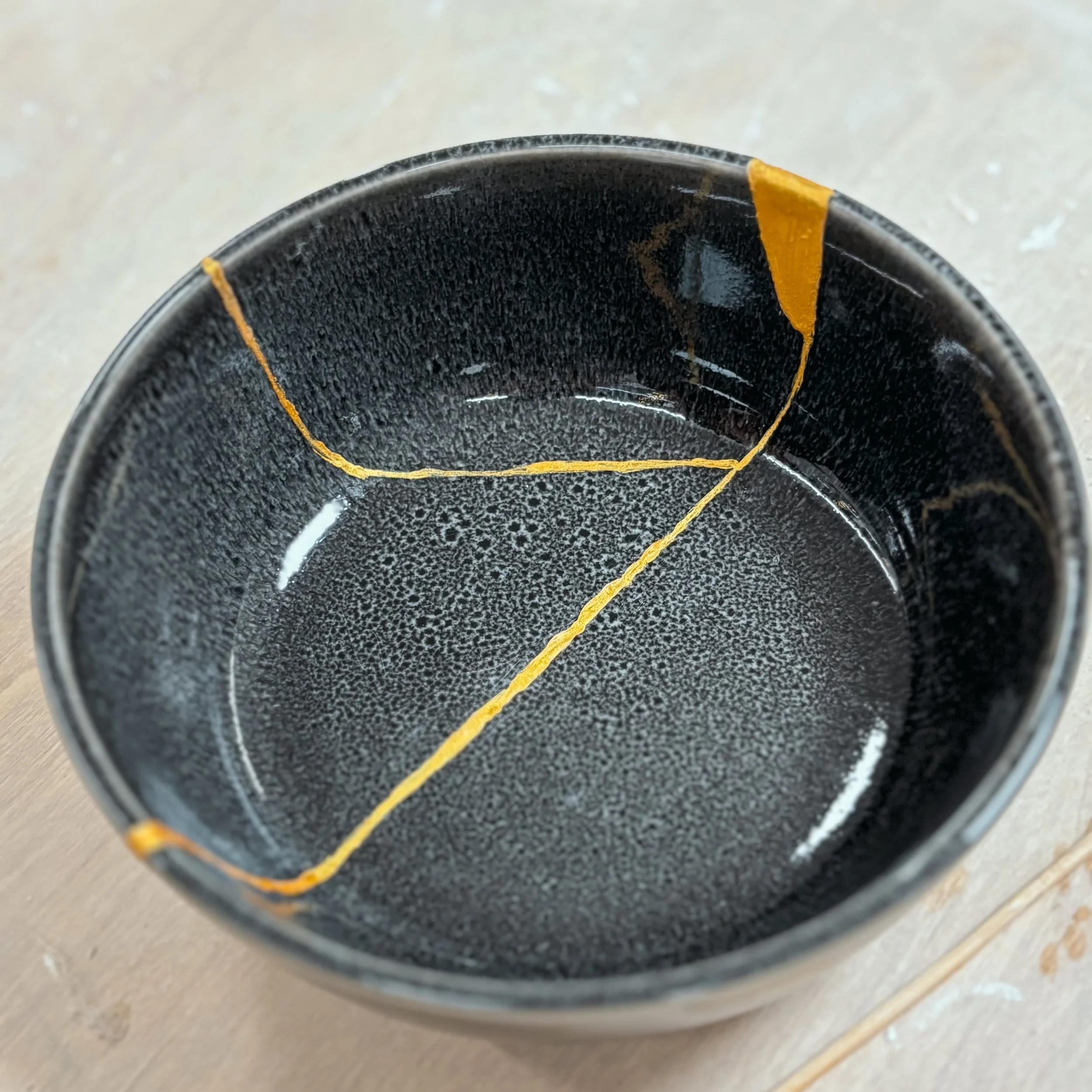 Tazza di ceramica rotta con crepe visibili all'interno, su una superficie di legno