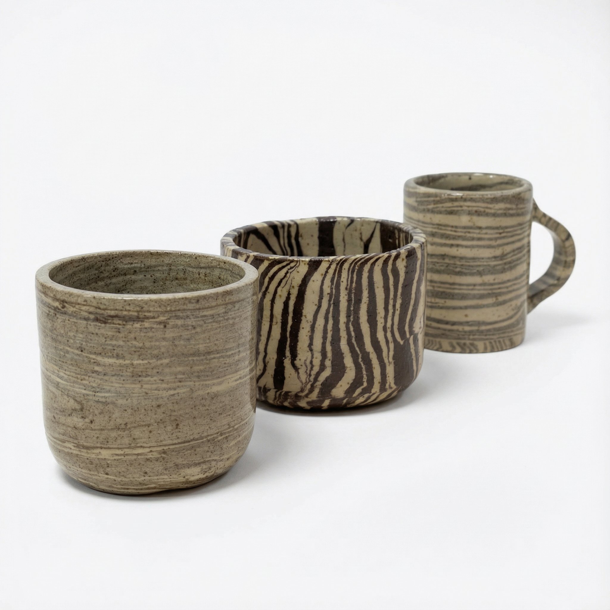 Tre tazze di ceramica con motivi zebrati e rigati su uno sfondo bianco.