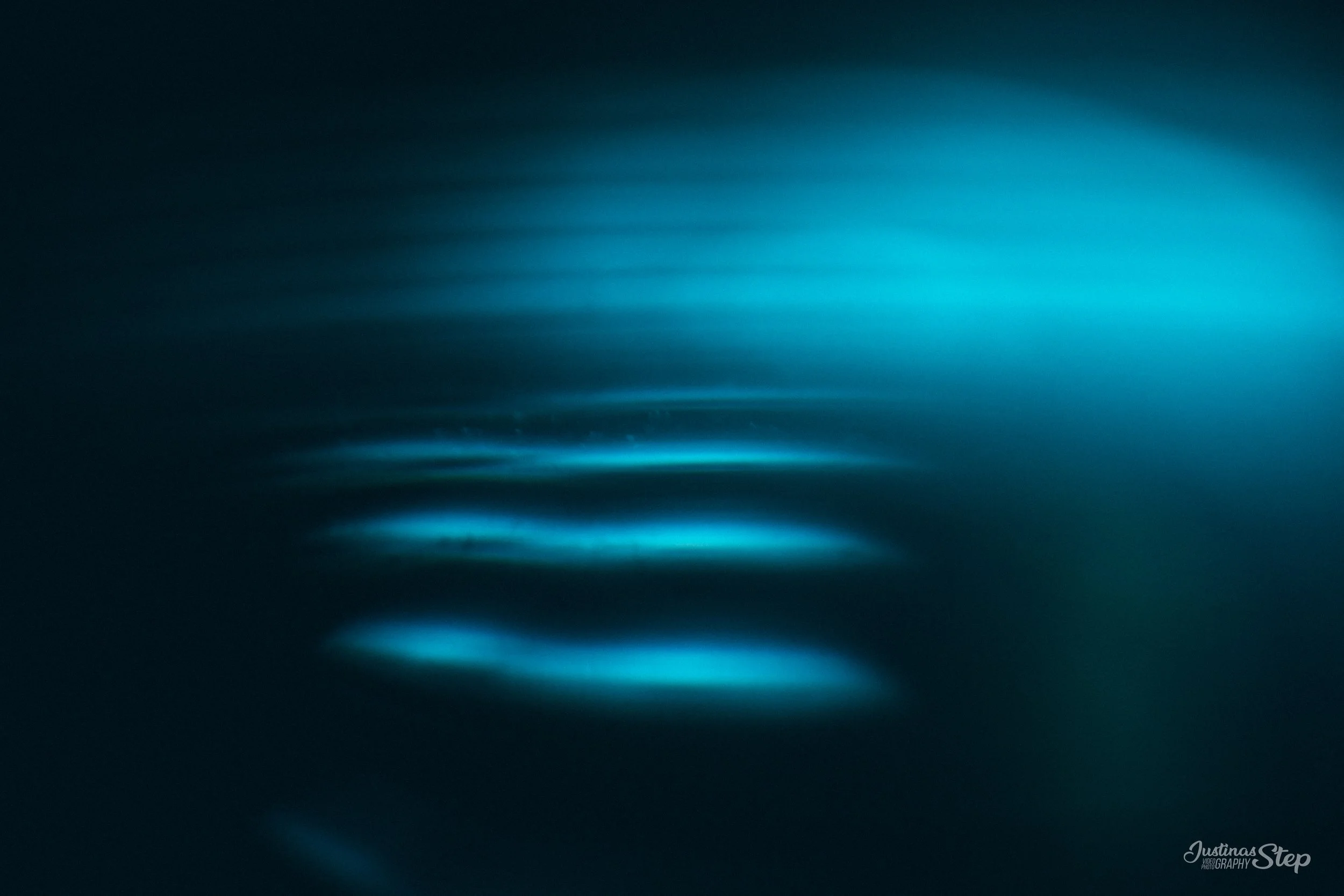 Abstract image of blue light streaks and reflections on a dark surface.