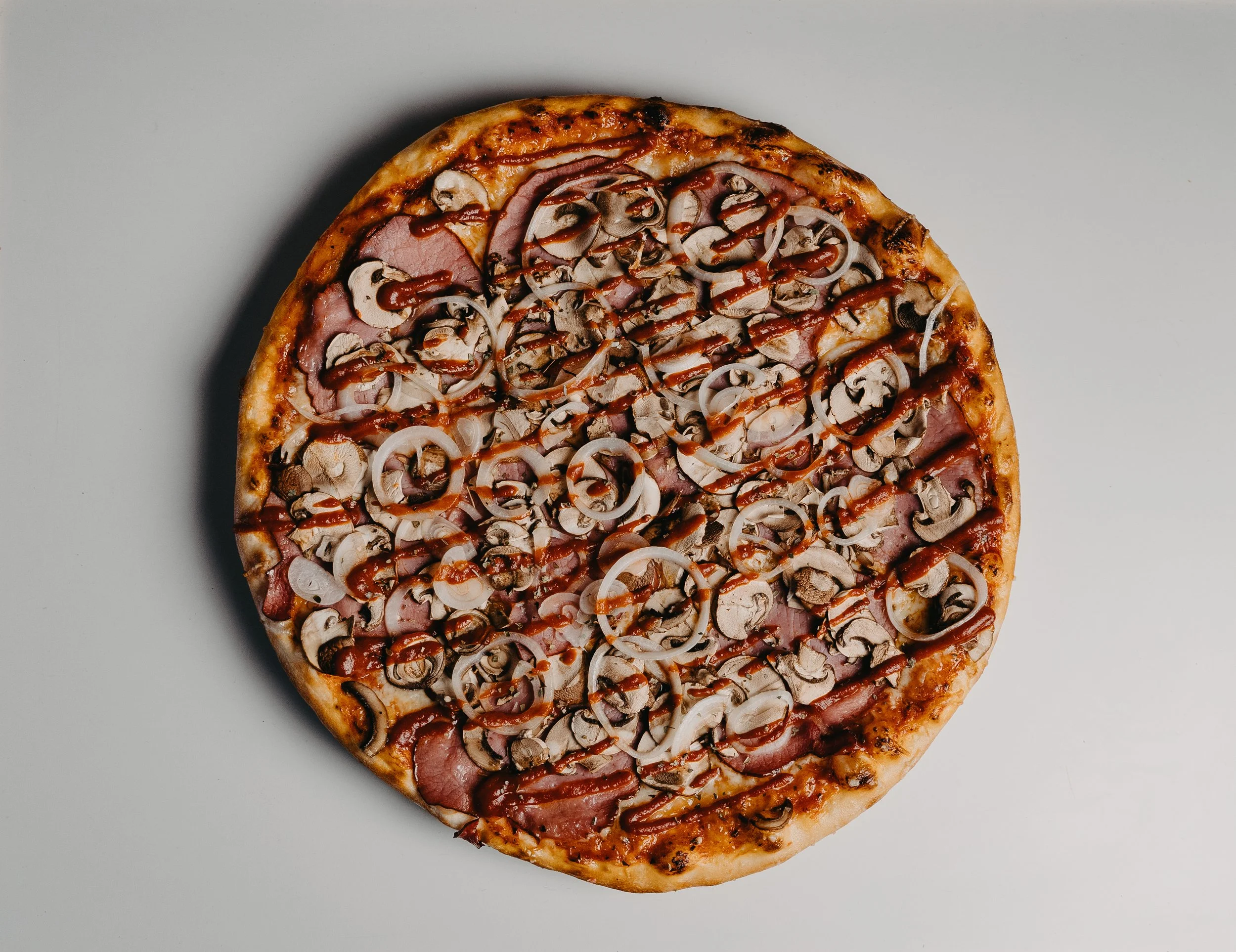 Whole mushroom and onion pizza with tomato sauce and cheese.