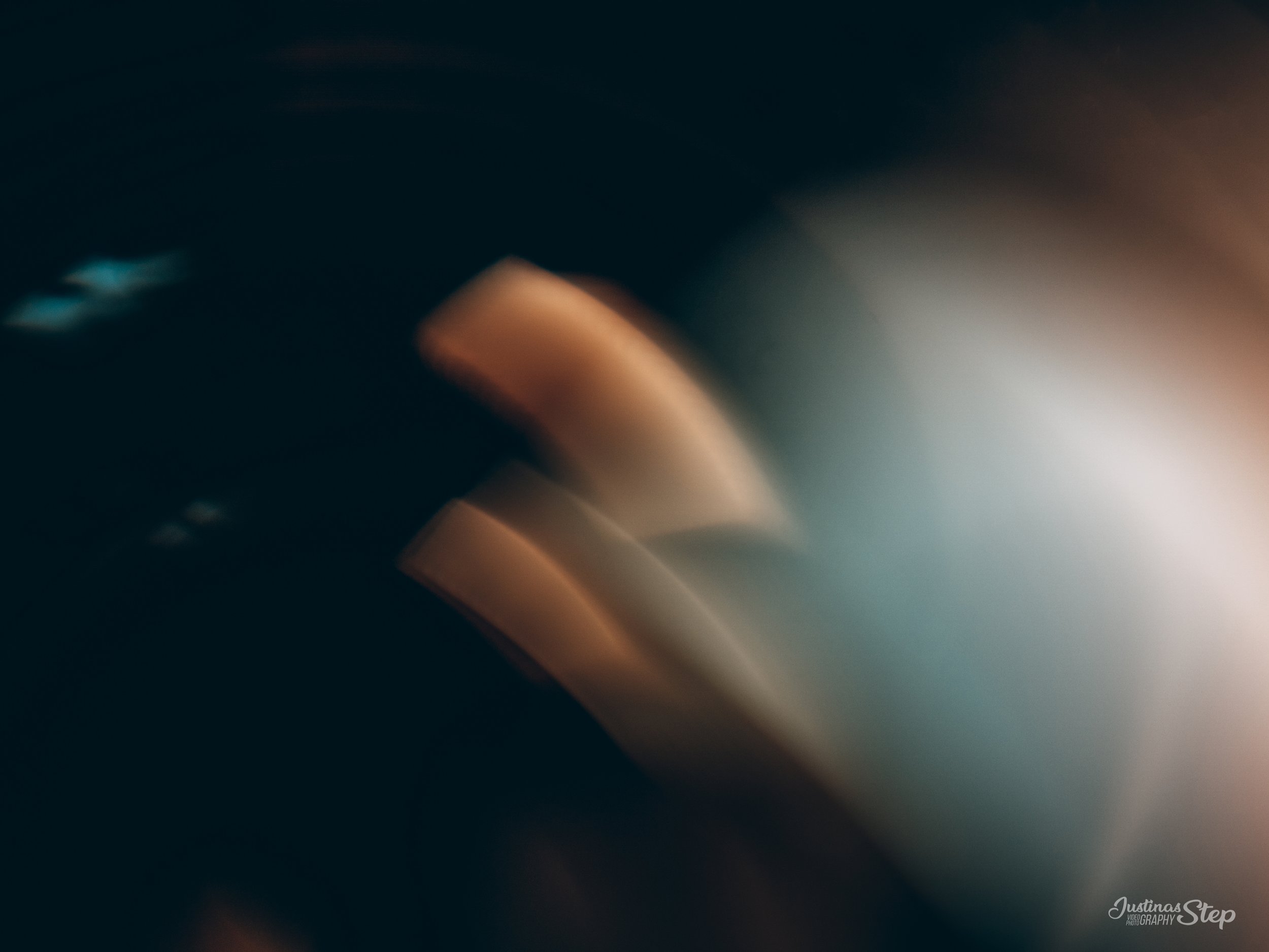 Abstract blurred image with dark background and warm light streaks creating a bokeh effect.