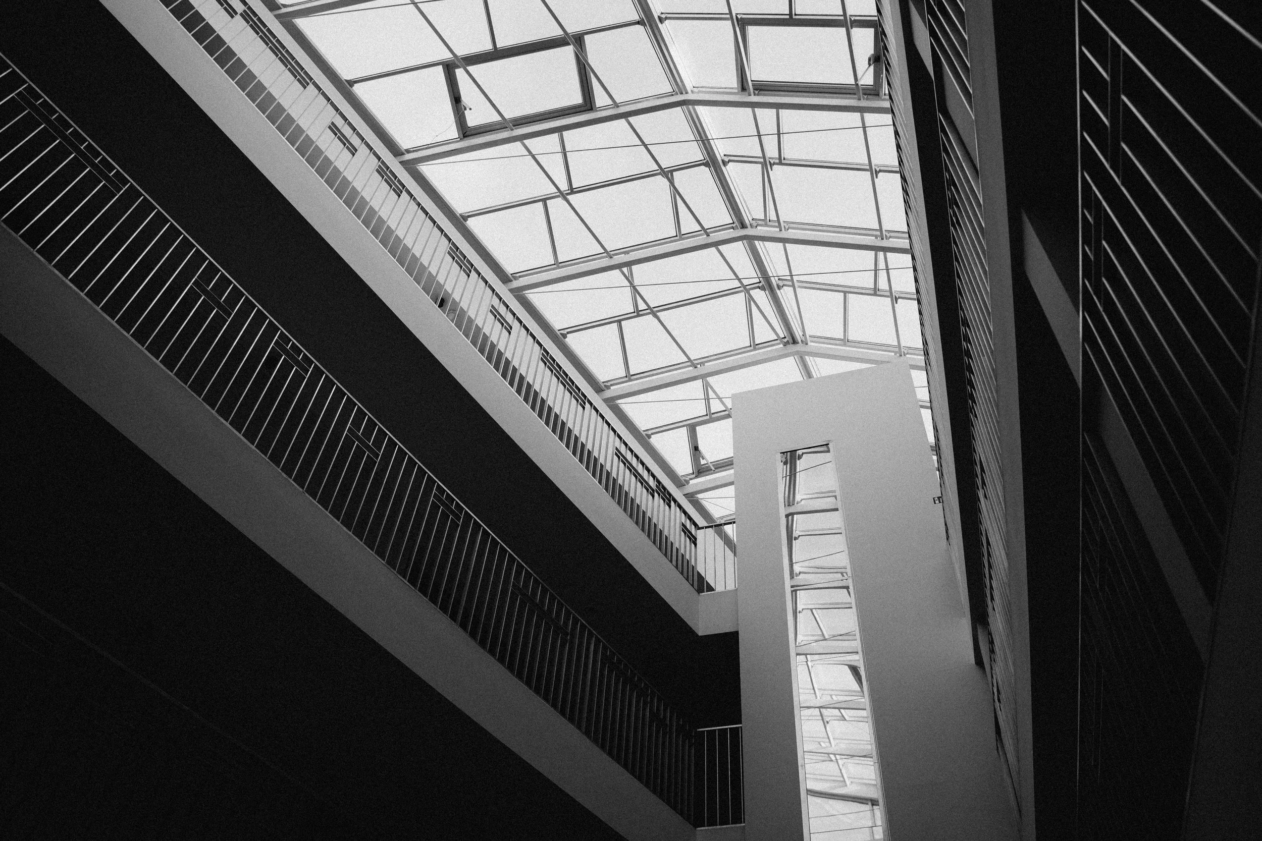 Modern architectural interior with a glass ceiling, multiple levels, and geometric lines.