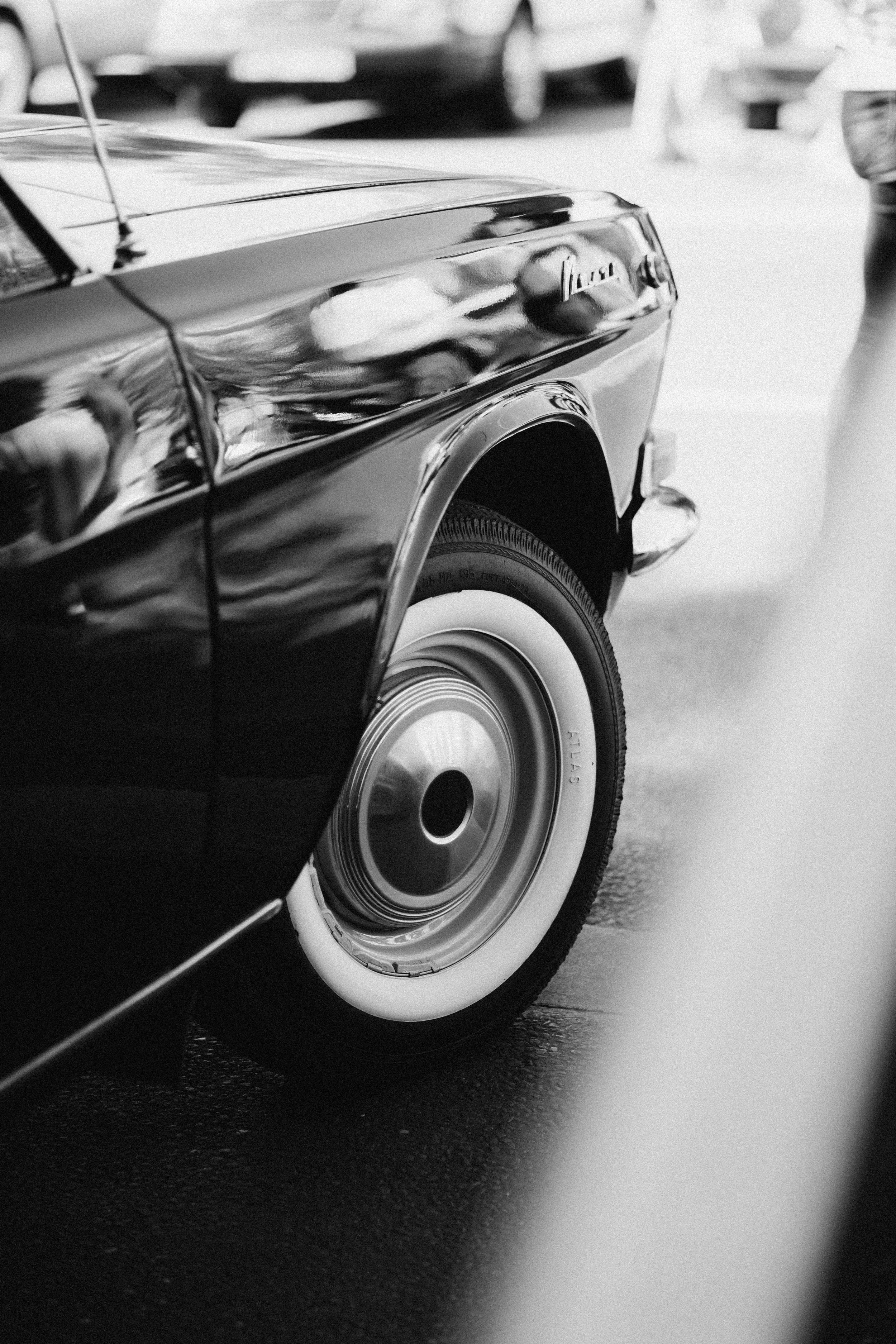 Close-up of a classic car's front wheel and fender, black and white image.