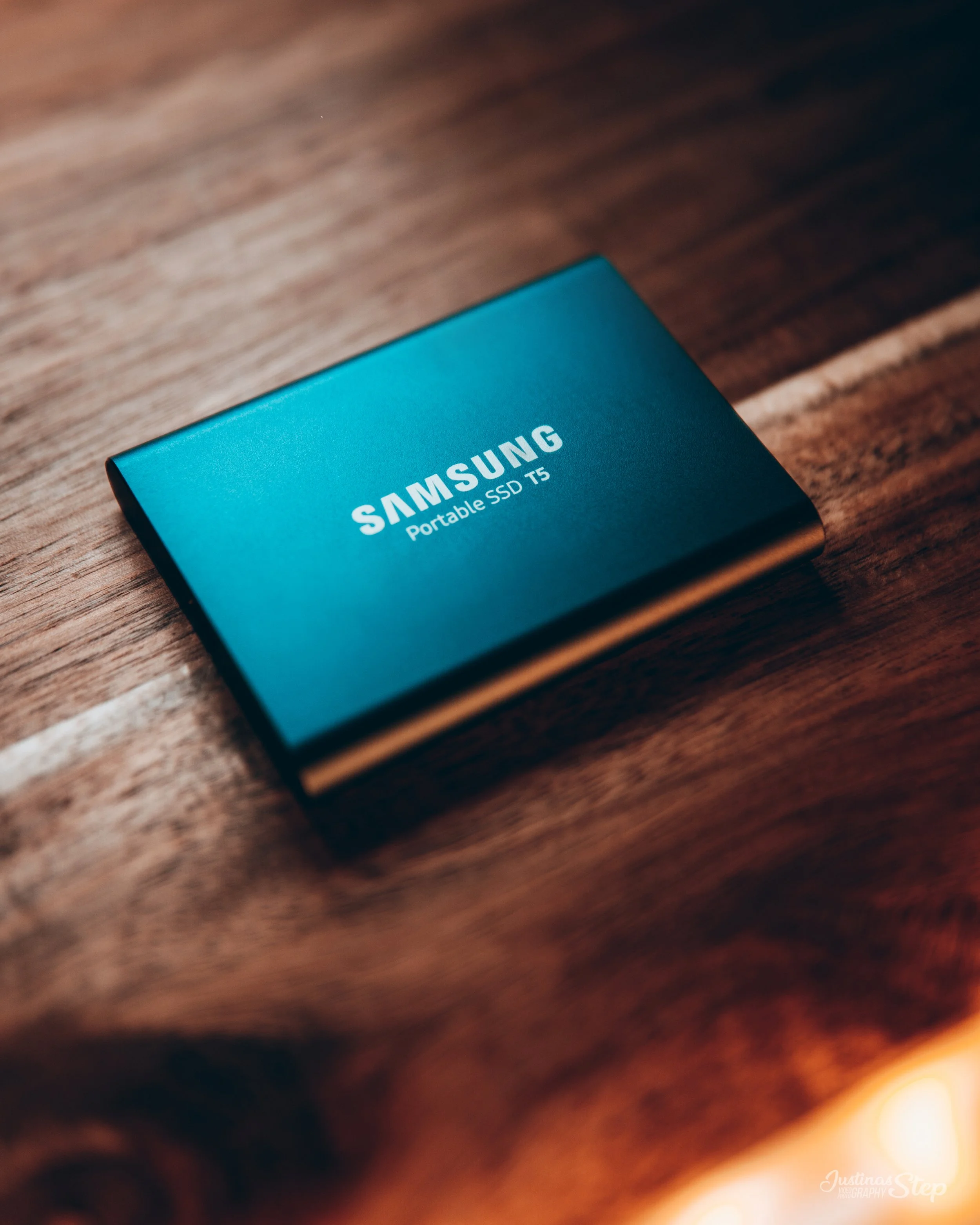 A blue Samsung portable SSD T5 on a wooden surface.