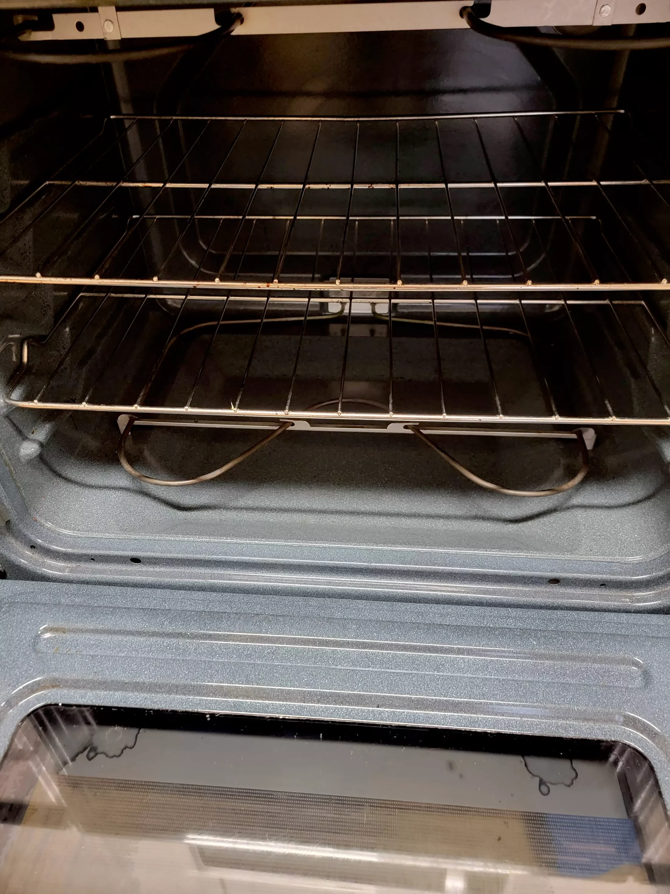 Inside view of an empty oven with racks and glass door.