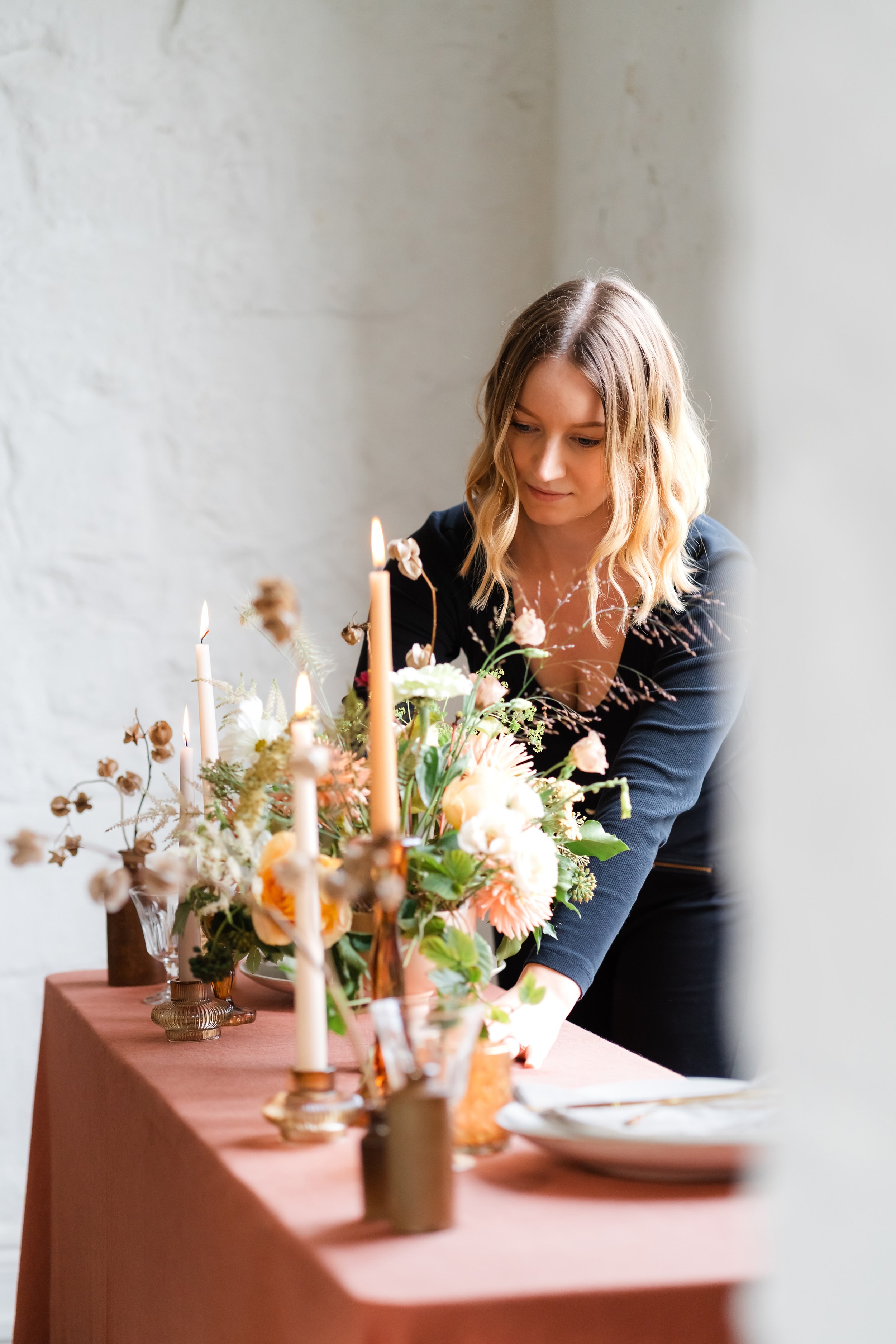 Florist setting up a wedding top table with blush floral arrangements