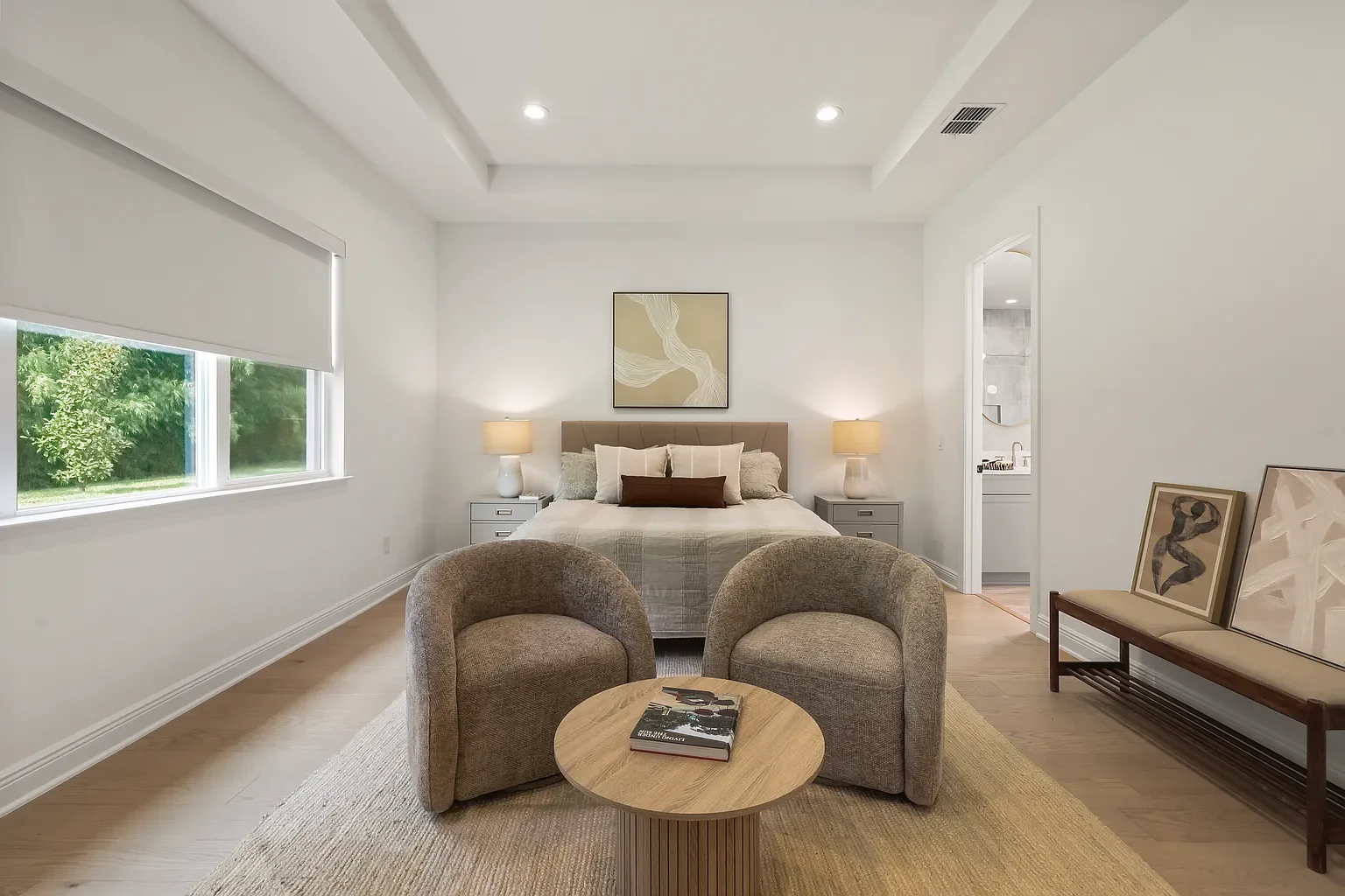 Bright bedroom with four large black-framed windows, light gray walls, a bed with gray bedding and throw pillows, nightstands with lamps, a wooden dresser, and a small bench near the window.