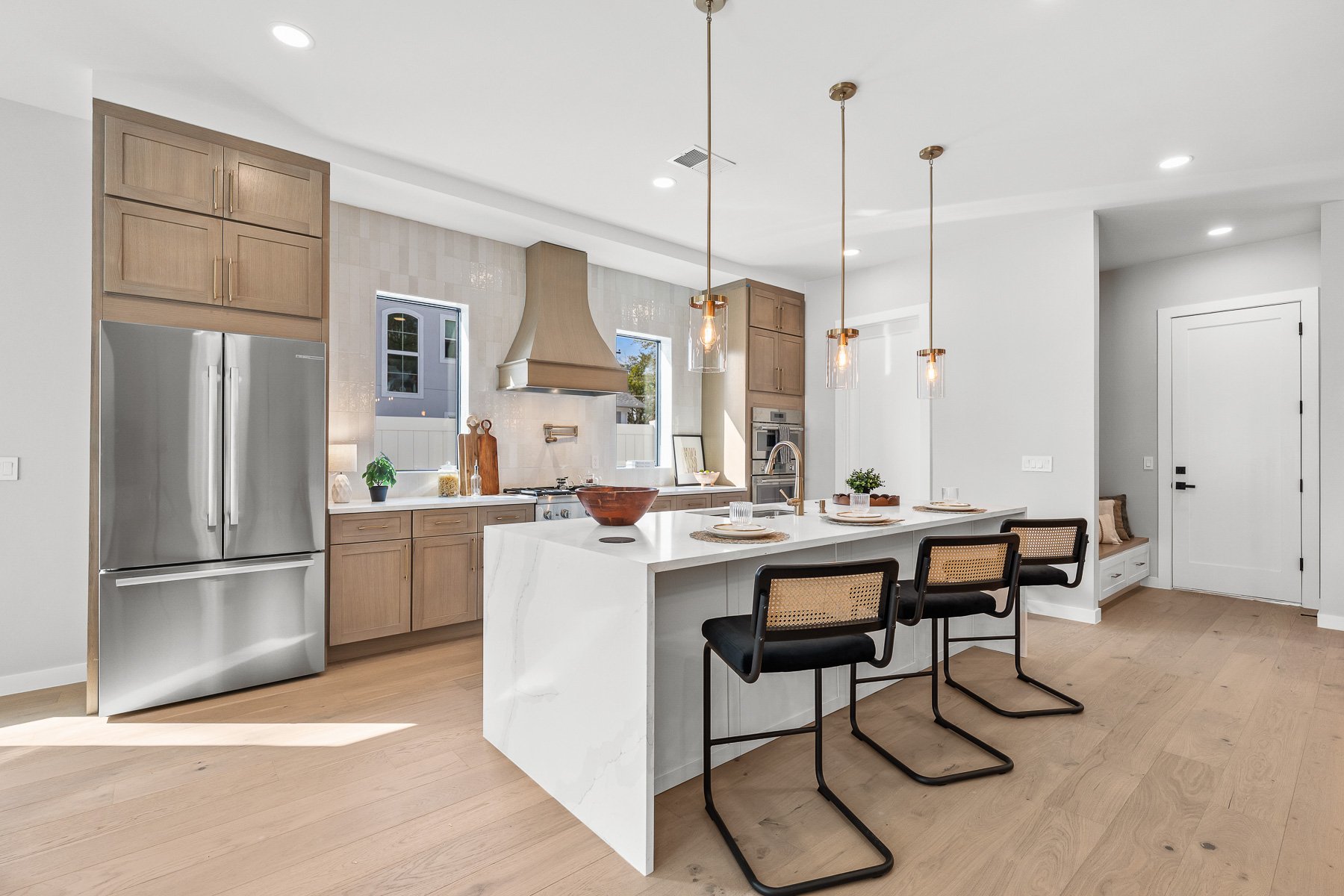 Open-concept living and dining area with wooden flooring, modern furniture, and large windows letting in natural light.