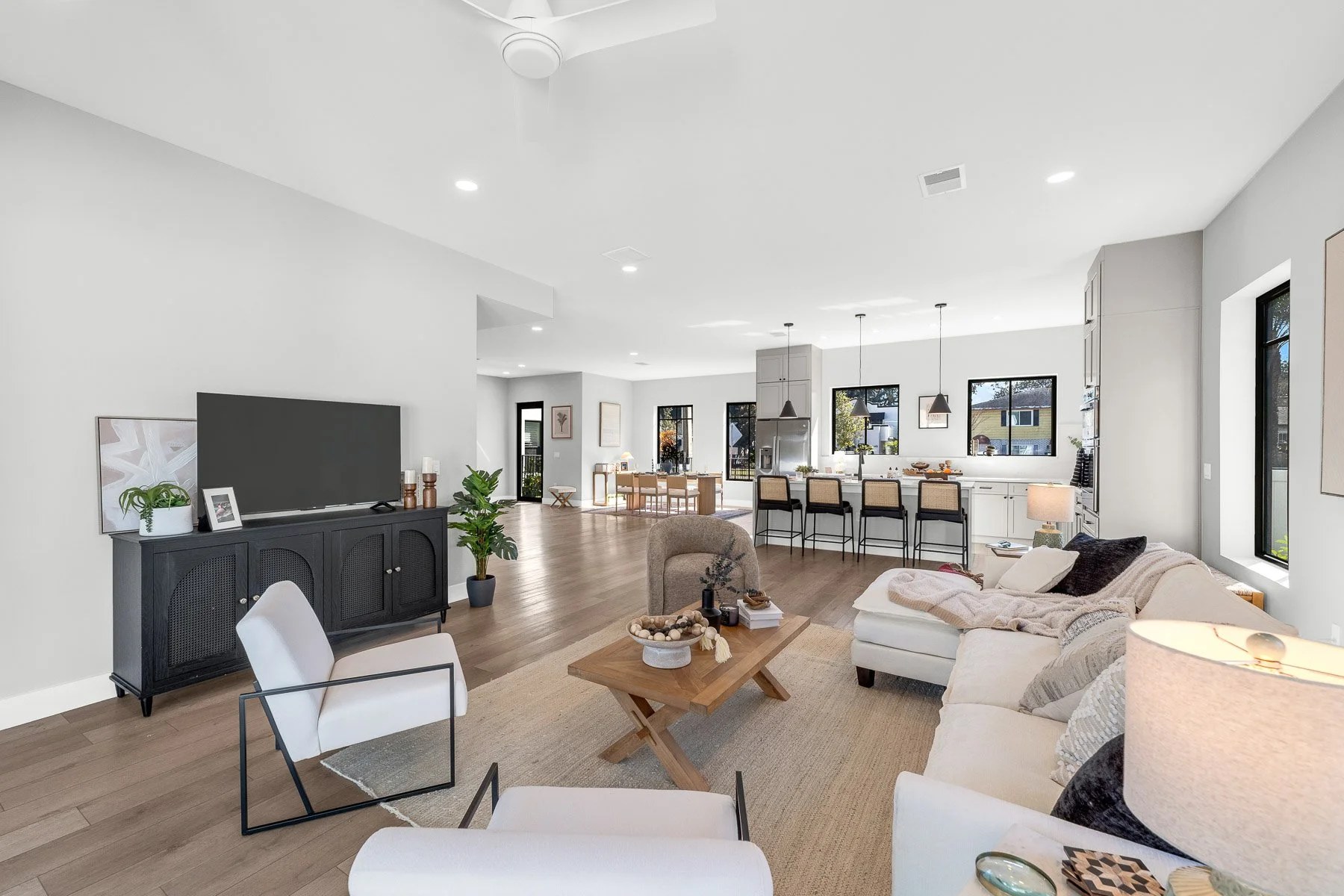 Modern kitchen with white cabinetry, a marble island with seating, stainless steel refrigerator, open shelving, and three pendant lights above the island.