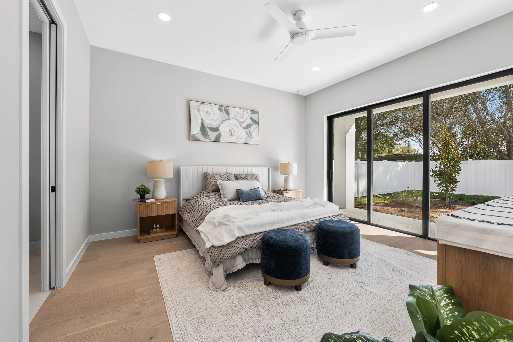 Modern kitchen with light wood cabinetry, white marble island, stainless steel refrigerator, open shelving, three pendant lights, and wood flooring