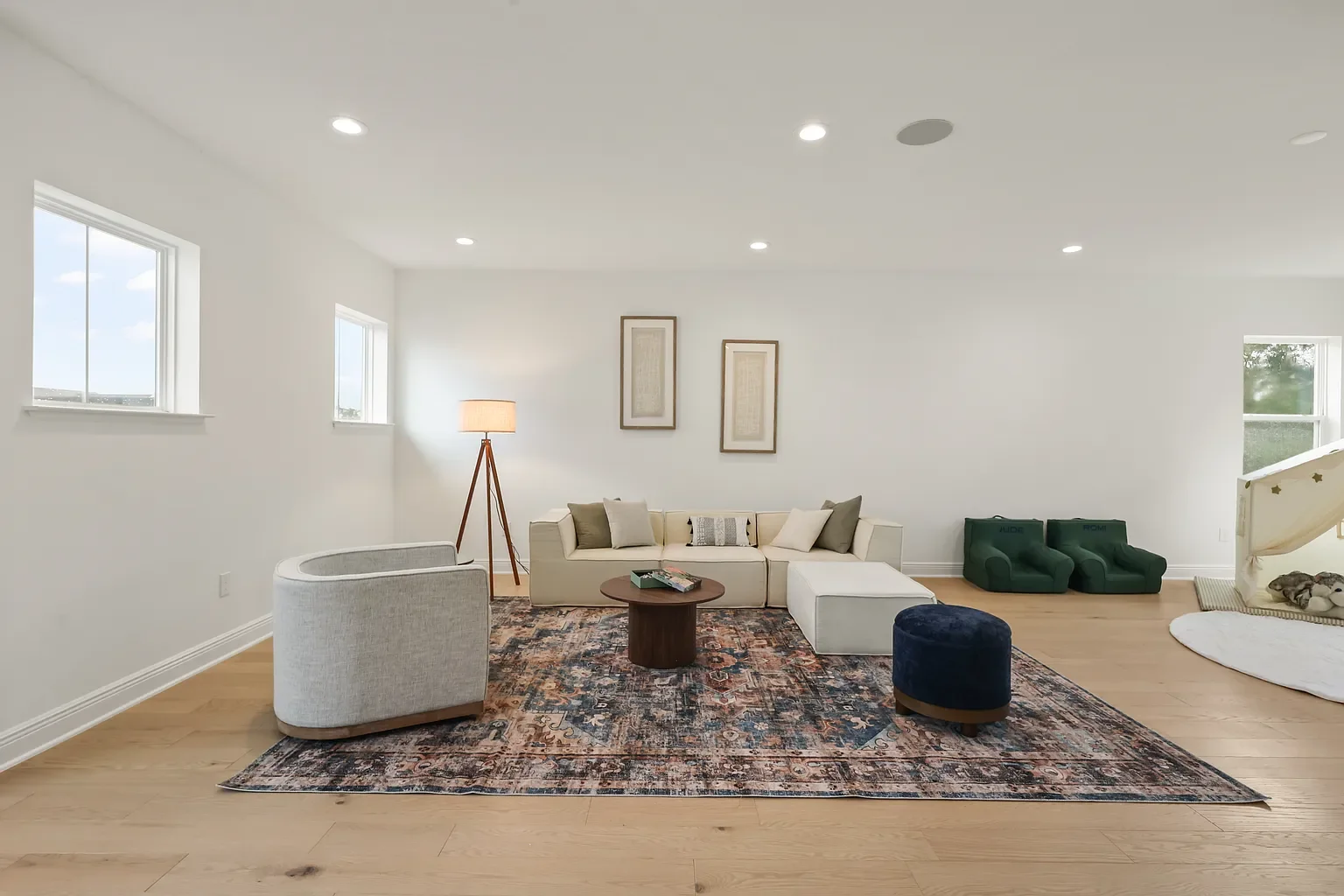 Open-concept living and dining area with wooden flooring, modern furniture, and large windows letting in natural light.