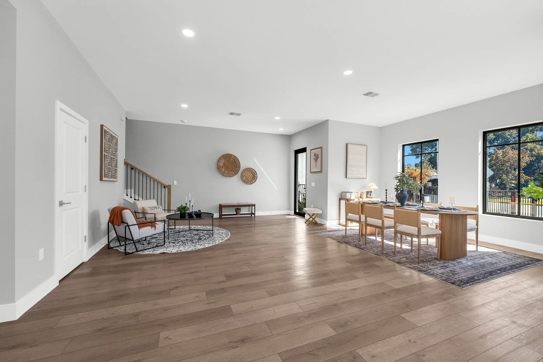 Modern kitchen with light wood cabinetry, white marble island, stainless steel refrigerator, open shelving, three pendant lights, and wood flooring