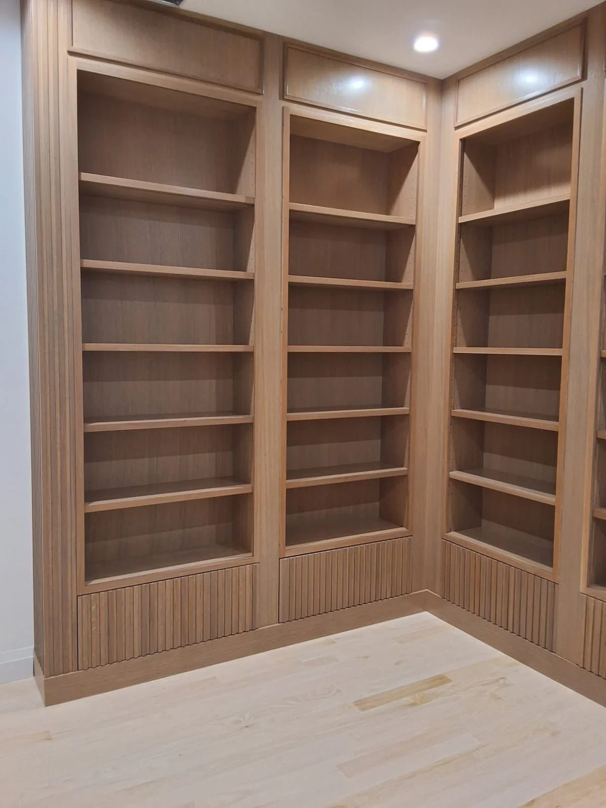 Wooden built-in bookshelves with multiple empty shelves in a corner of a room.