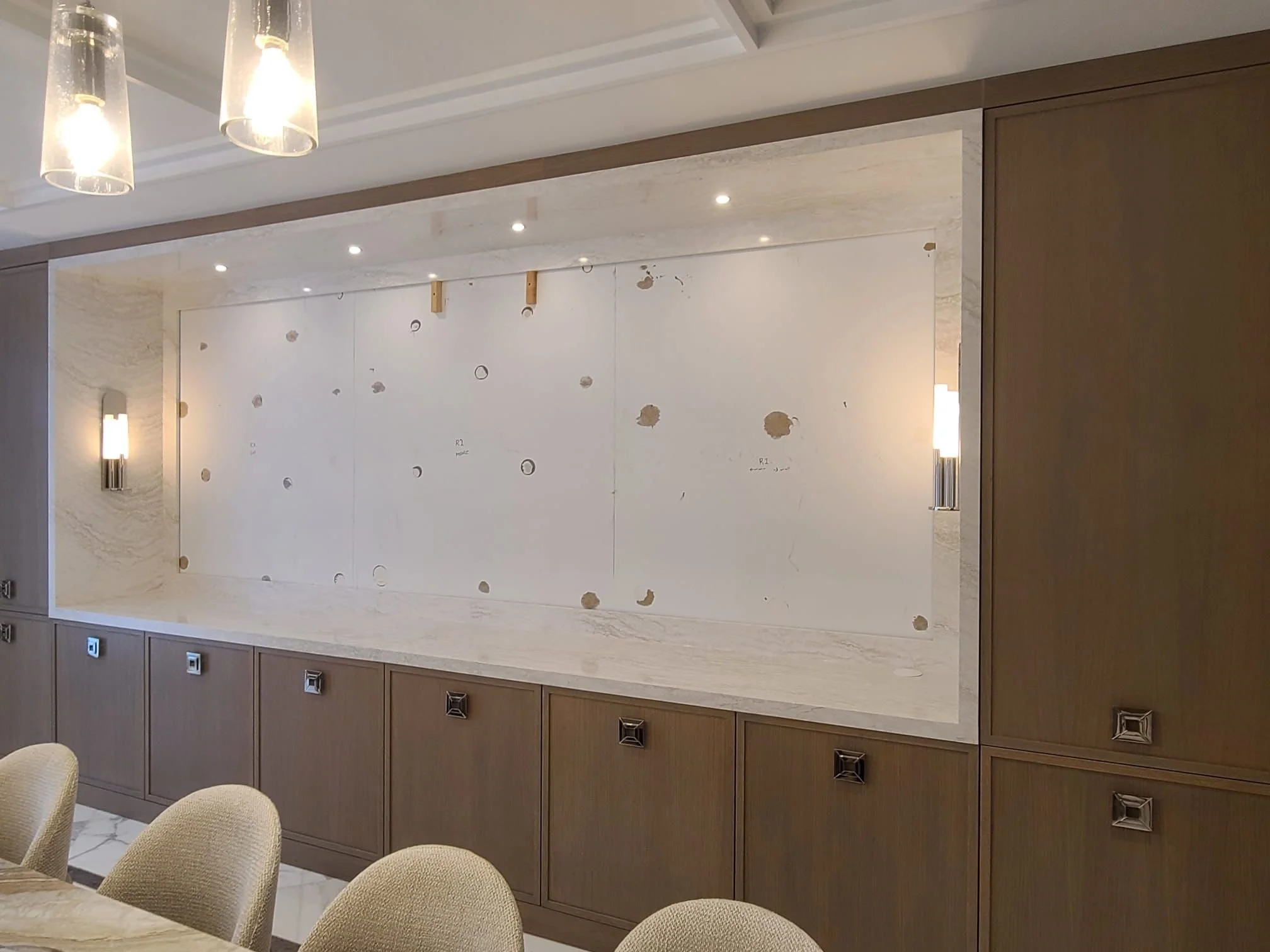 Interior of a modern dining room with a recessed area for a television, currently empty, with wall sconces and built-in cabinetry.