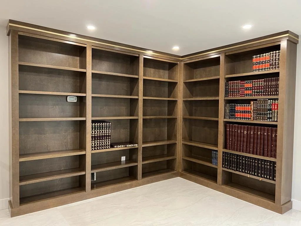 Large wooden bookshelf with mostly empty shelves, some books on the right side, in a room with white walls and ceiling.