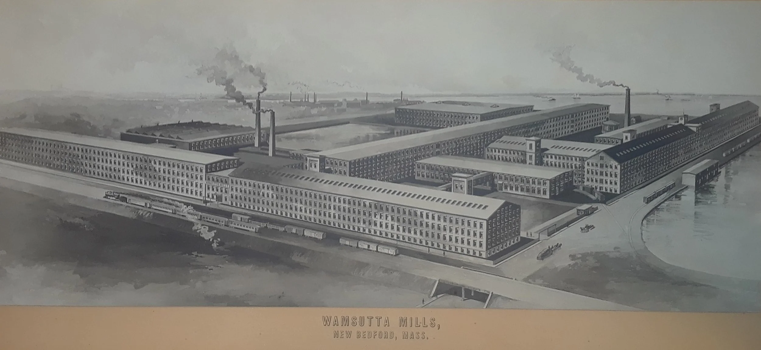A black-and-white illustration of Wamsutta Mills in New Bedford, Massachusetts, showing large factory buildings with smokestacks emitting smoke, trains on tracks, and a river nearby.
